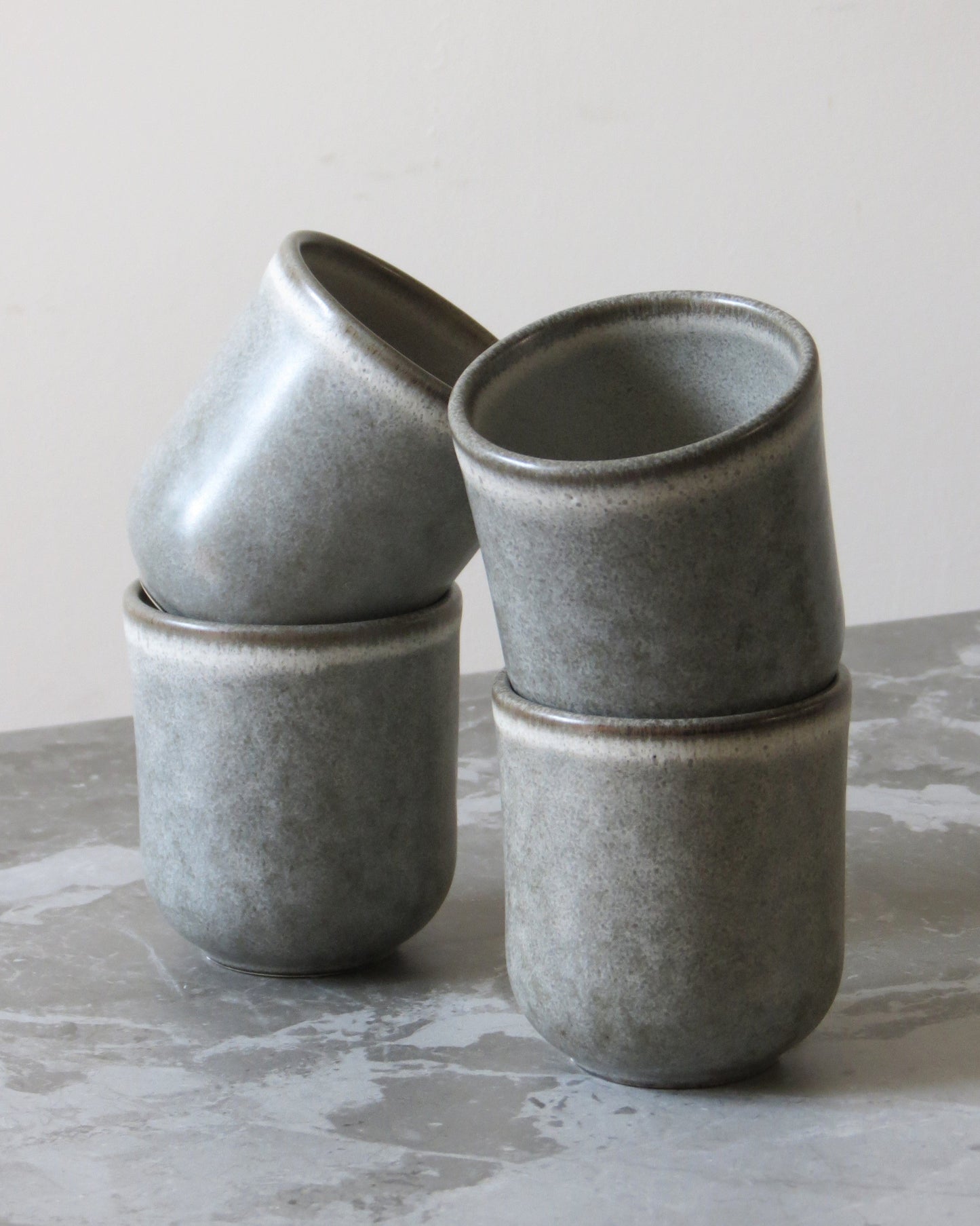 Set of grey ceramic cups stacked on a textured surface with a neutral background