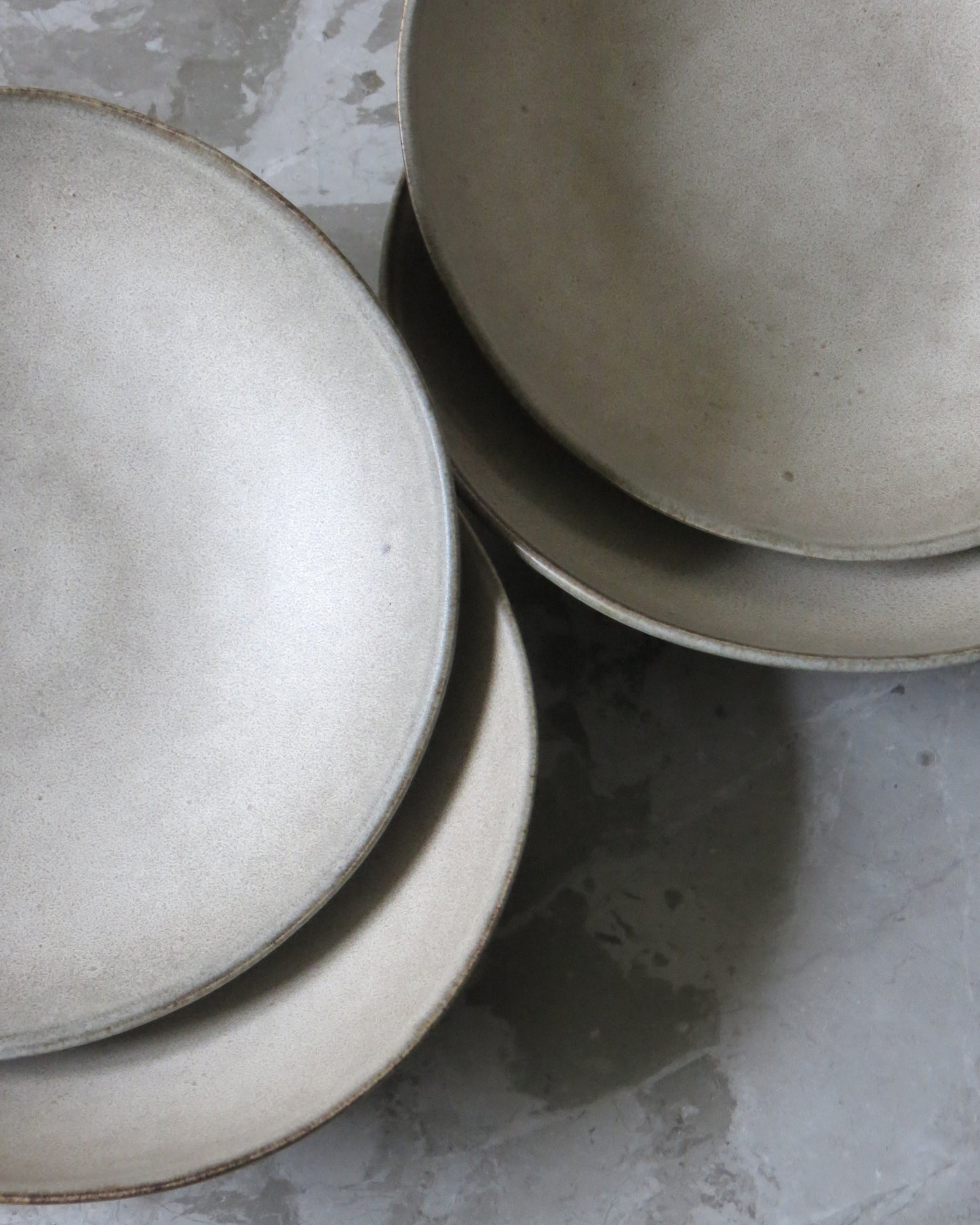 A close-up of a grey, matte-finished ceramic pasta bowl with another one partially visible in the background.