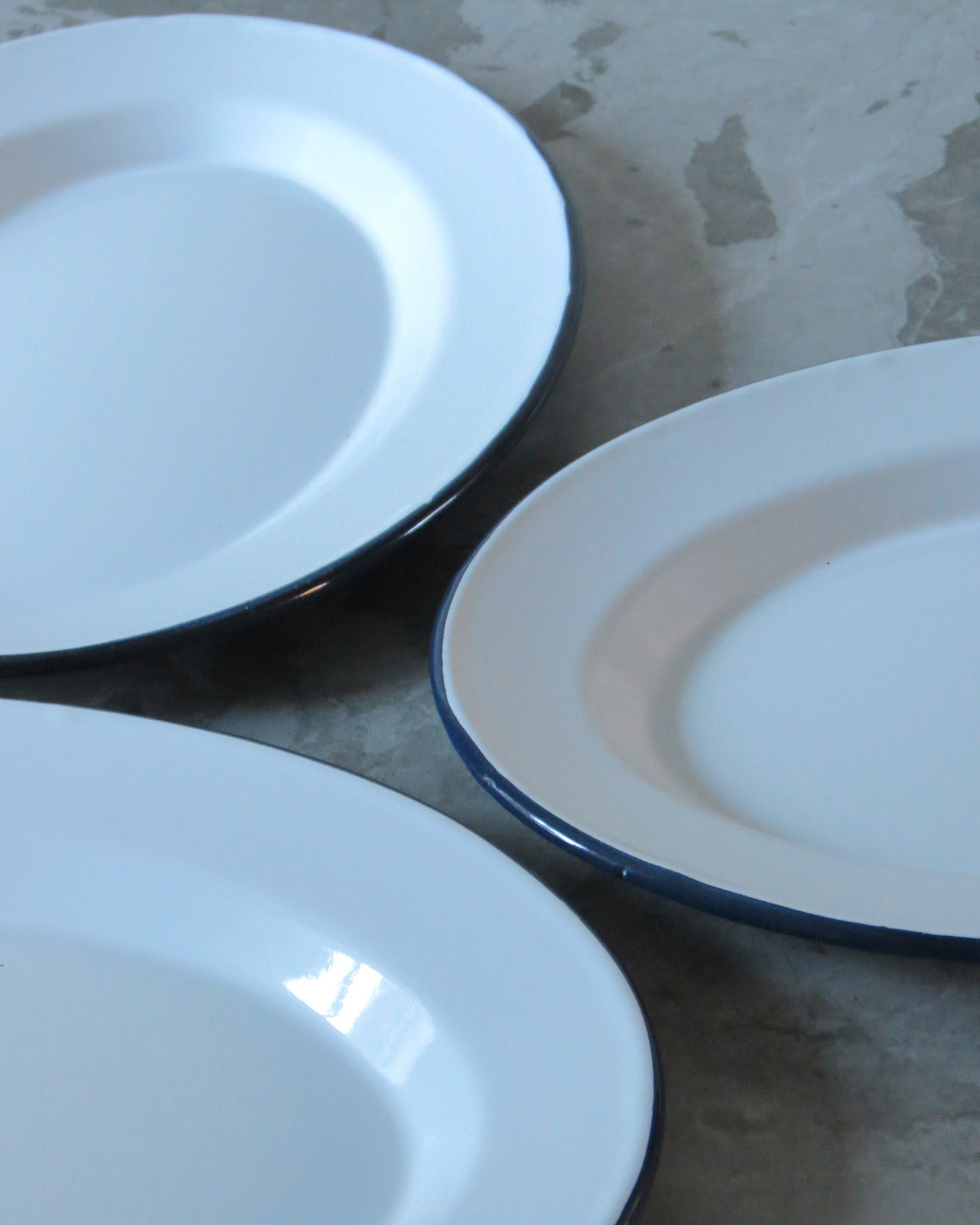 Three white plates with blue rims on a textured surface