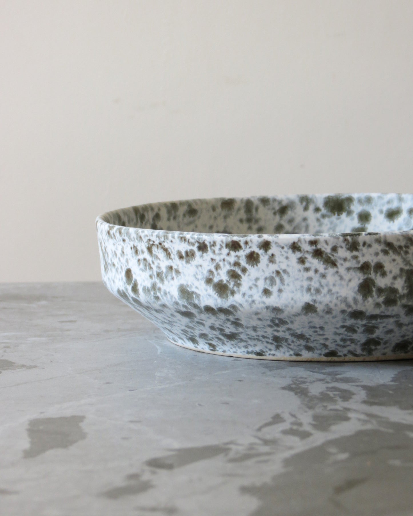 Speckled ceramic bowl on a textured surface with a neutral background