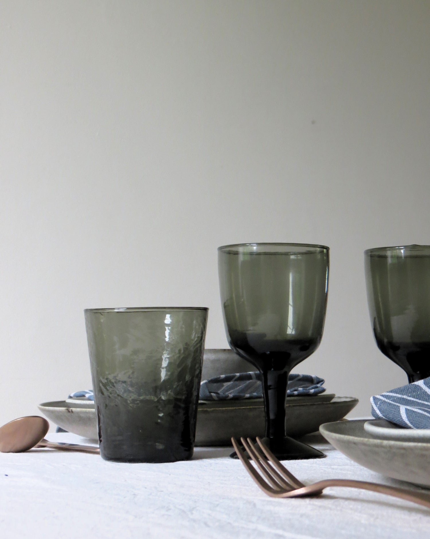 Smoked glasses on  alight table, a tumbler and a wineglass. 
