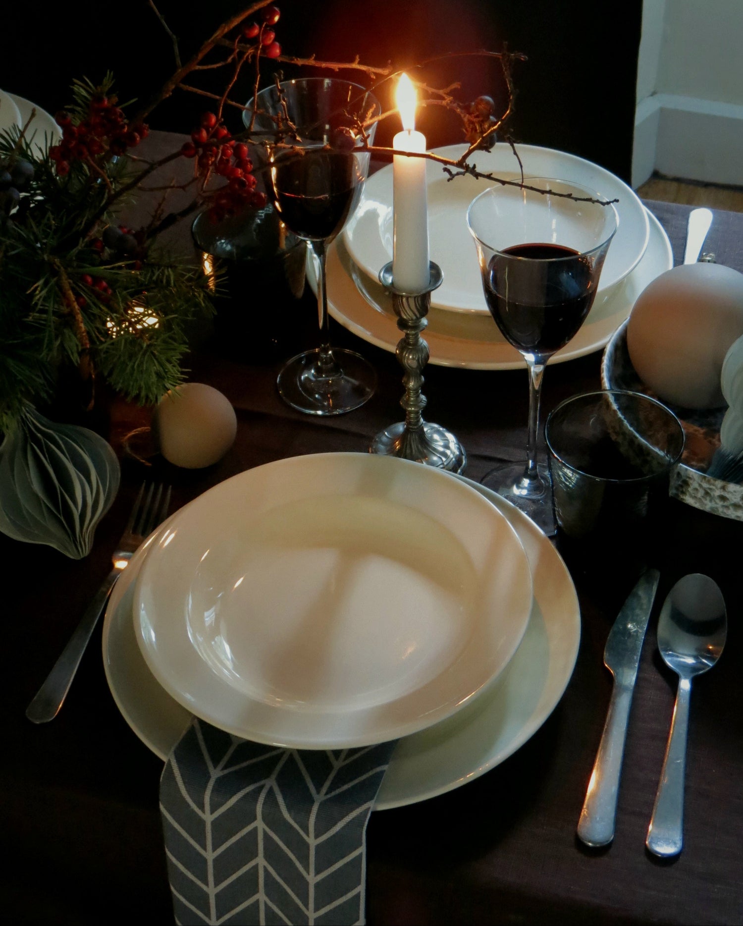 detail of tablescape with brown tablecloth ivory plates chevron napkins and a candle 