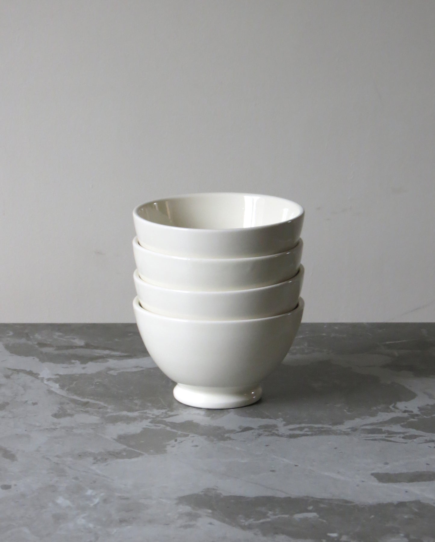 A white ceramic cereal bowl placed on a grey surface, with a simple and elegant design.