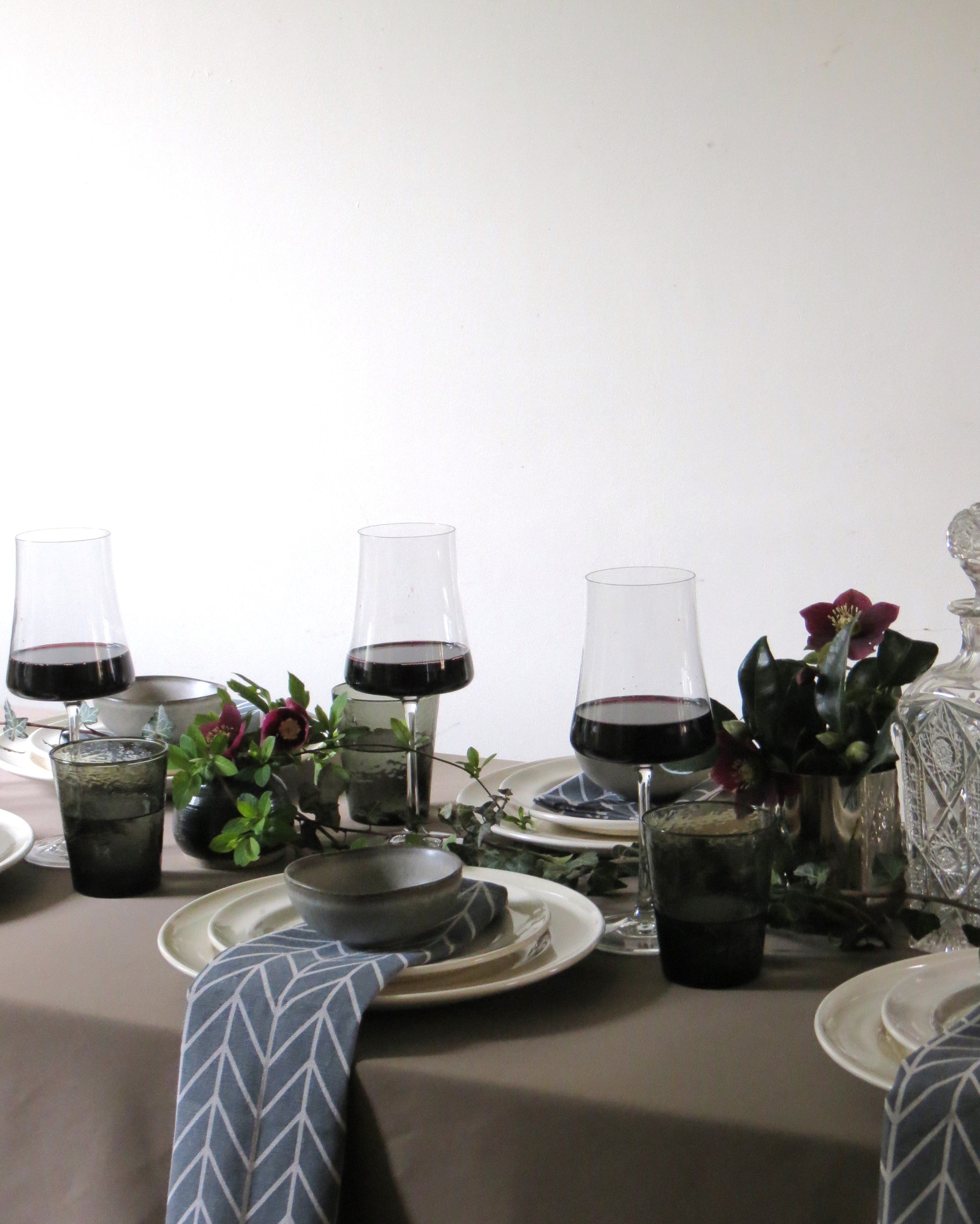 Dinner table setting with wine glasses, plates, and decorative elements on a neutral background