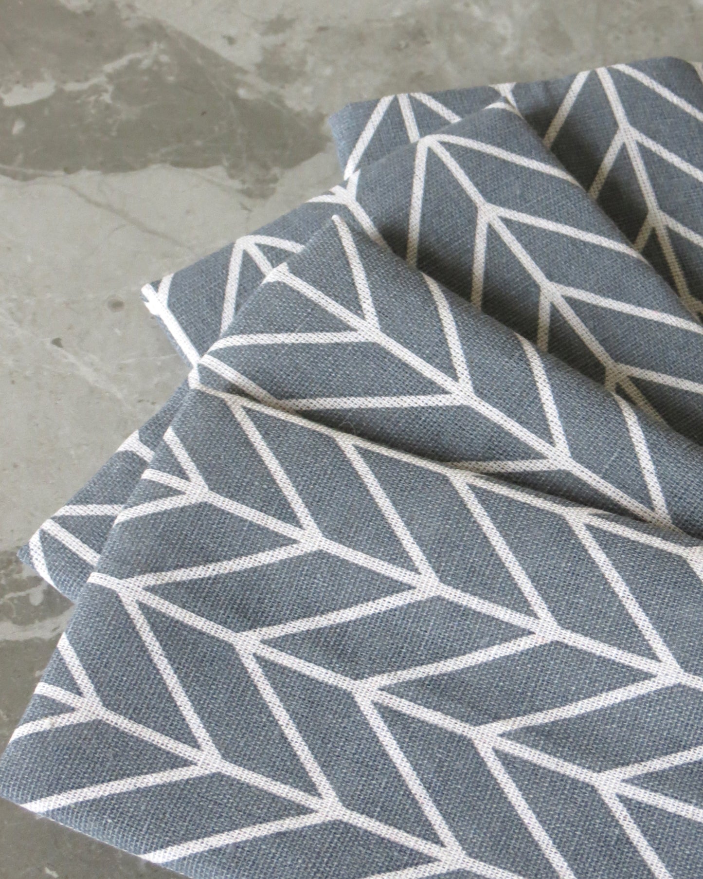 Grey fabric with white geometric pattern on a concrete surface