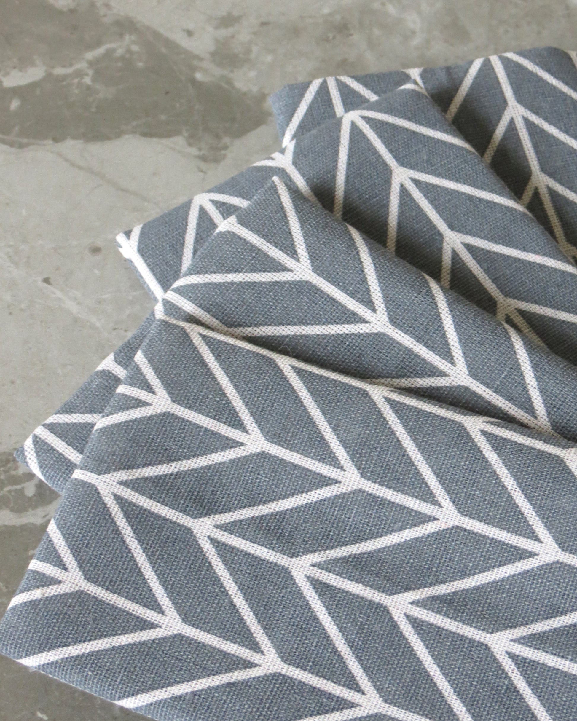 Grey fabric with white geometric pattern on a concrete surface