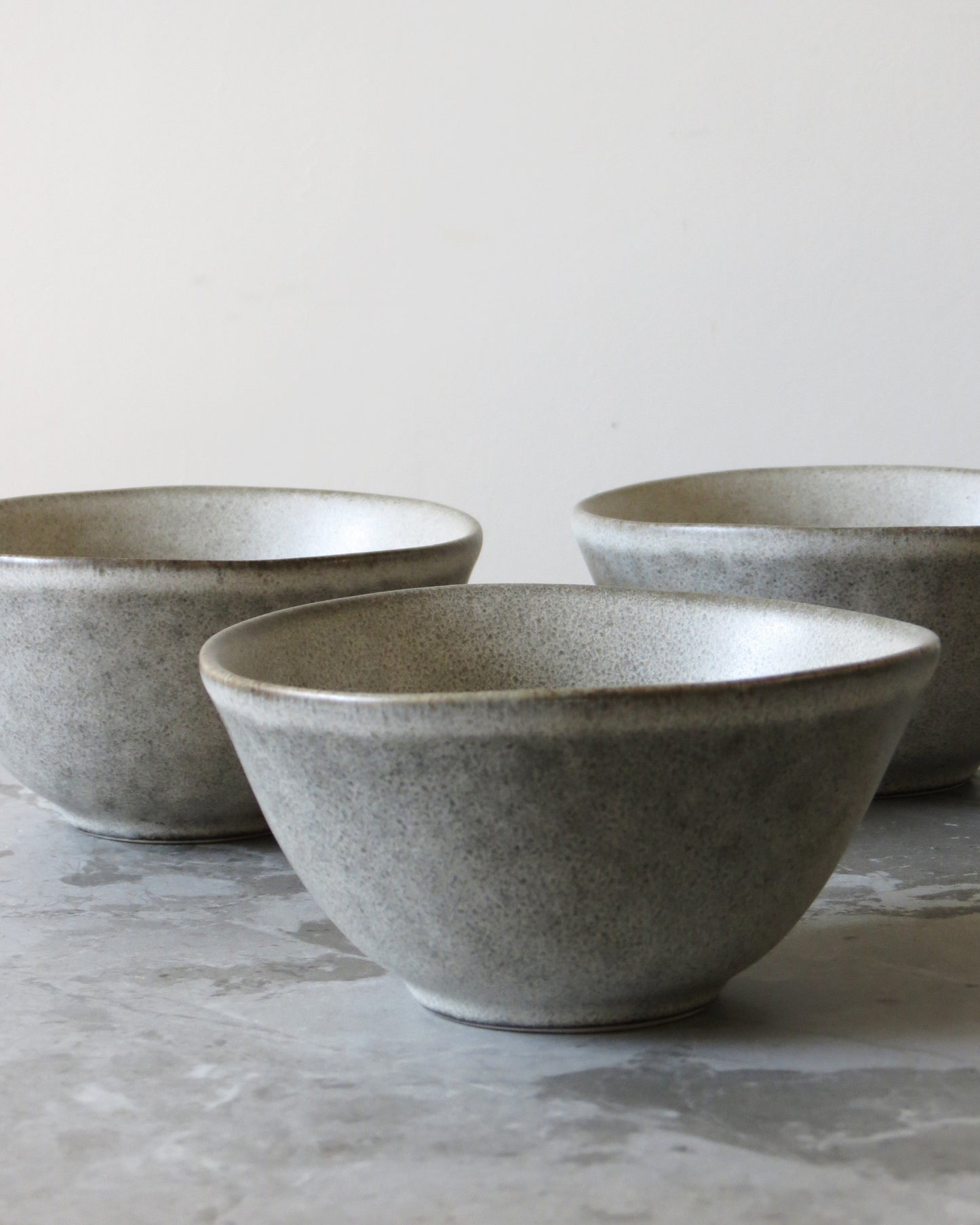 Three grey ceramic bowls on a light grey surface with a neutral background