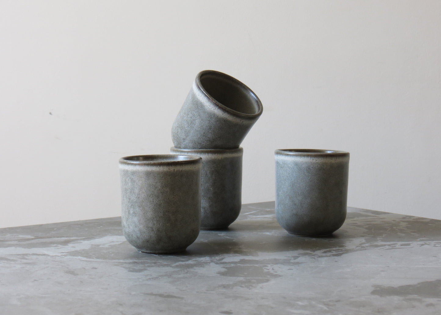 Set of grey ceramic cups on a marble surface with a neutral background