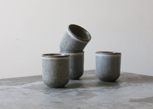 Set of grey ceramic cups on a marble surface with a neutral background