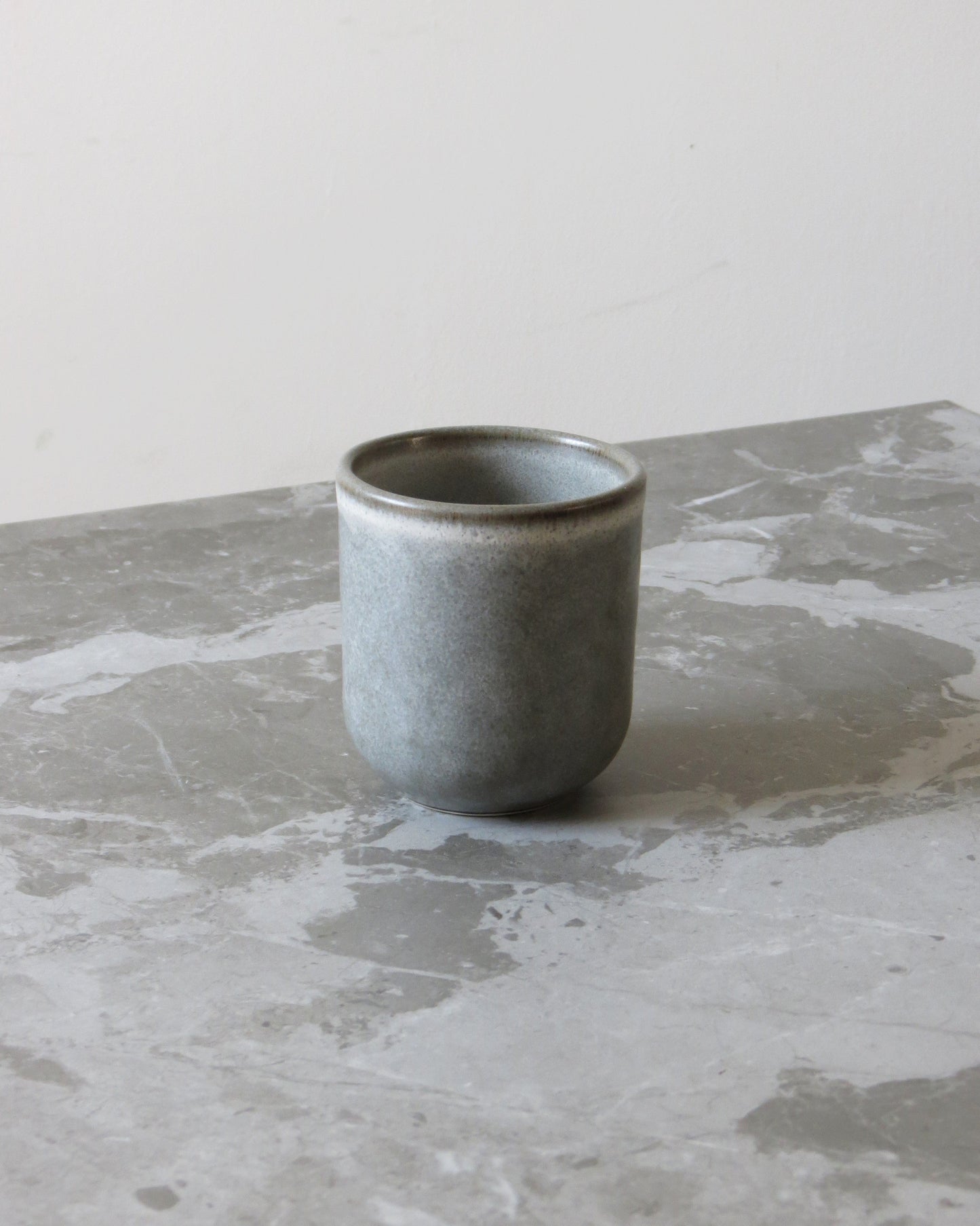 Grey ceramic cup on a marble surface with a neutral background