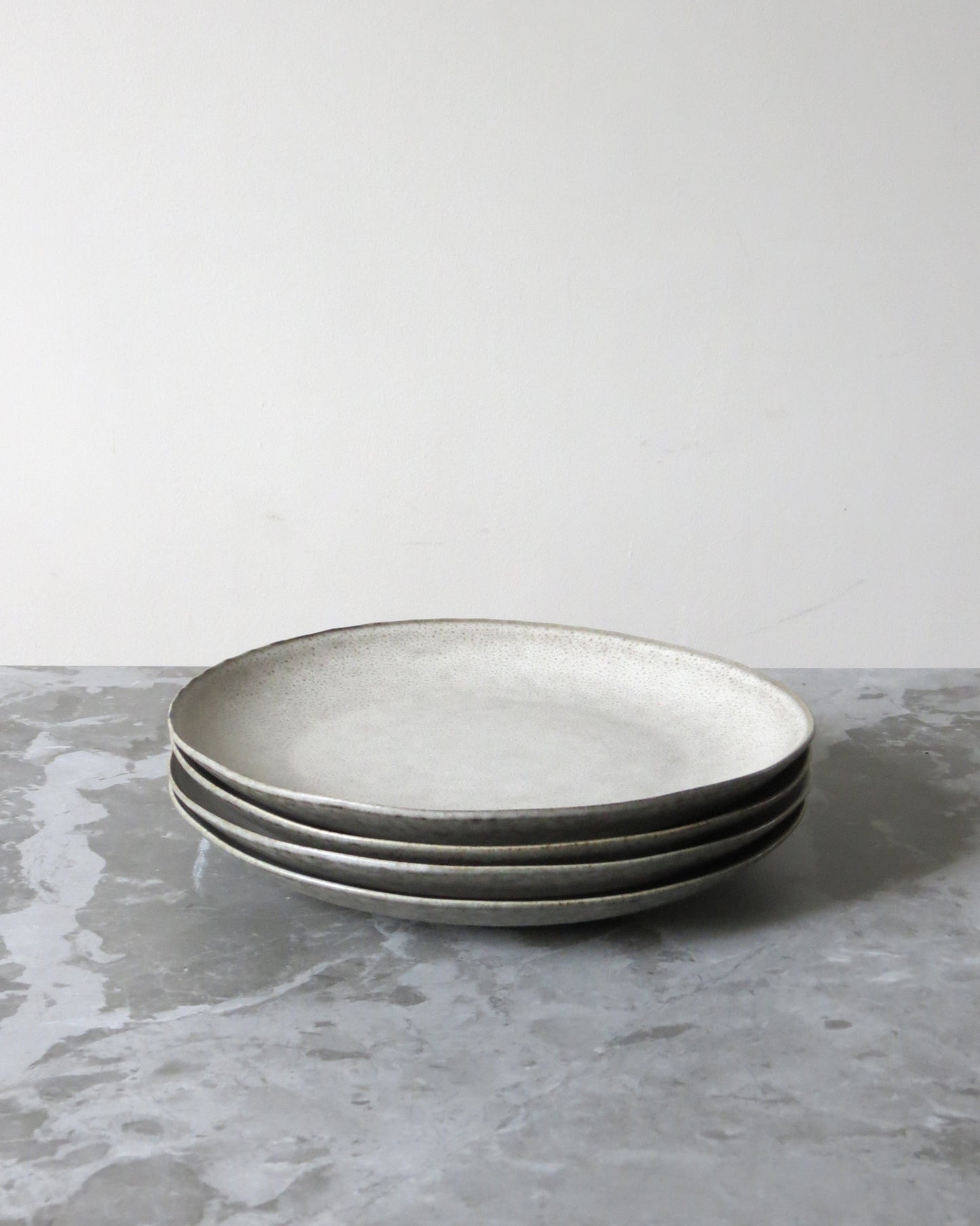 Three grey ceramic plates stacked on a grey surface with a white background