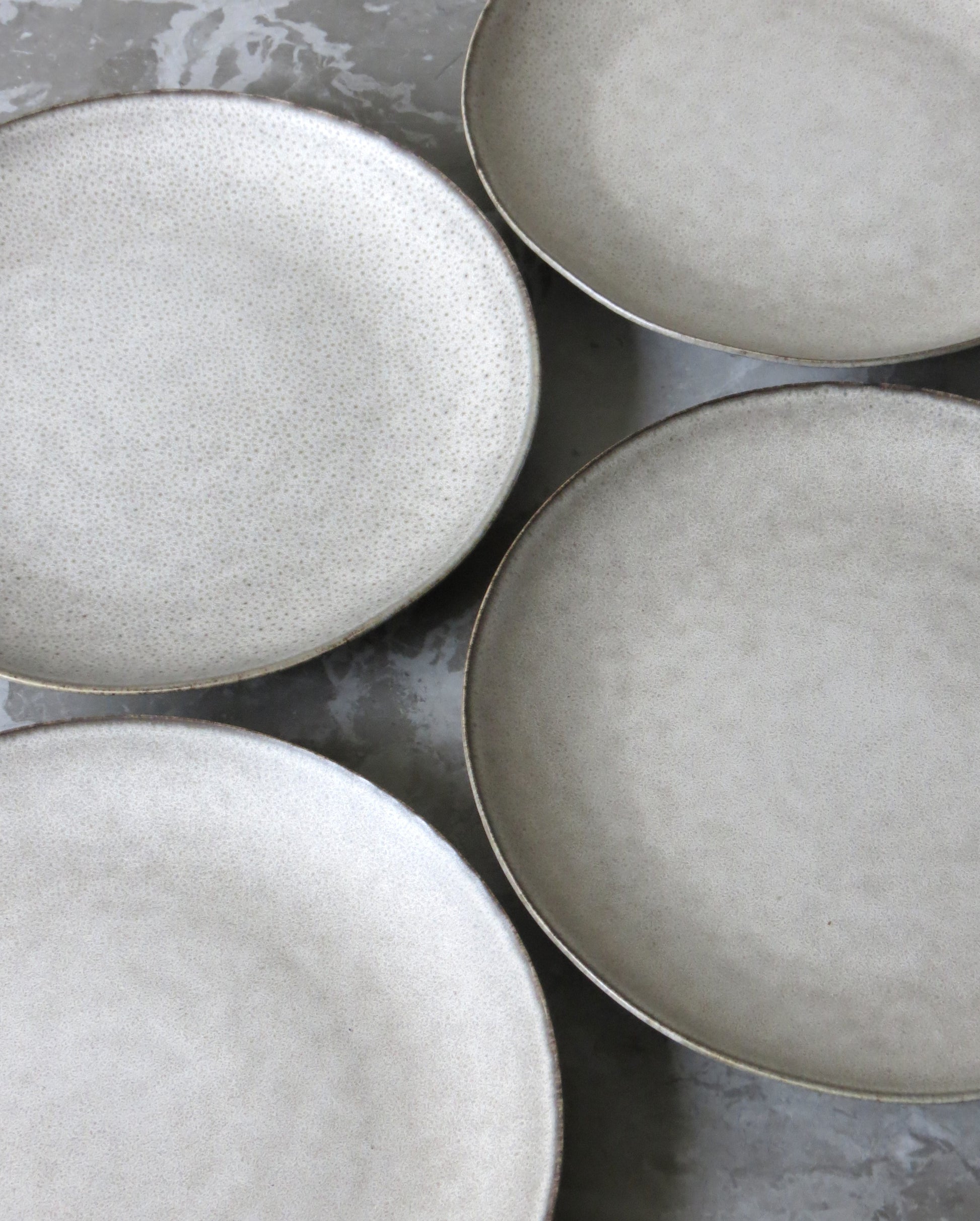 Four ceramic plates with a textured finish on a grey surface.