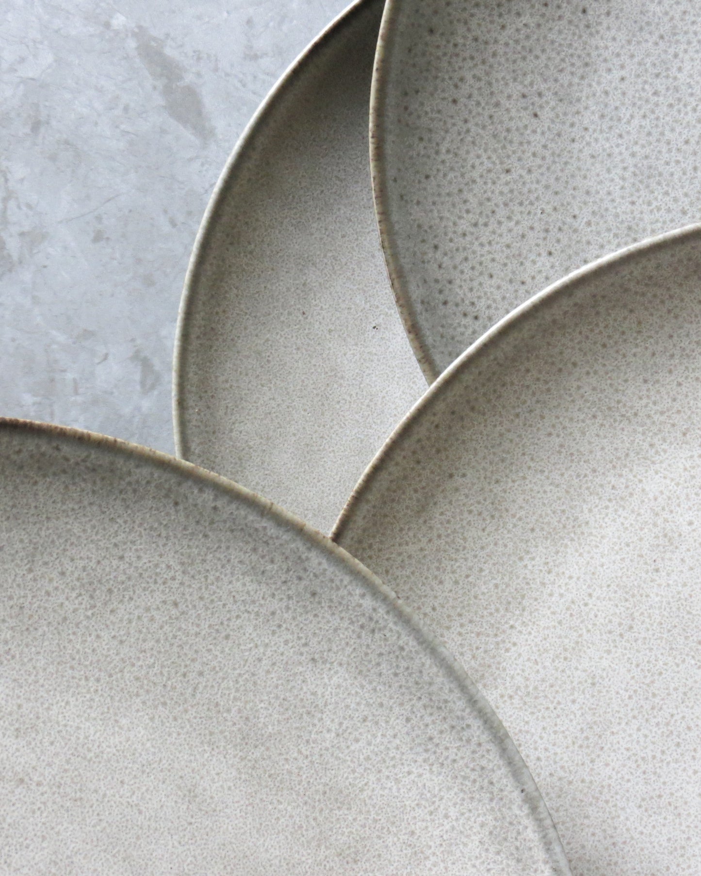 Close-up of three ceramic plates with a textured surface on a light grey background