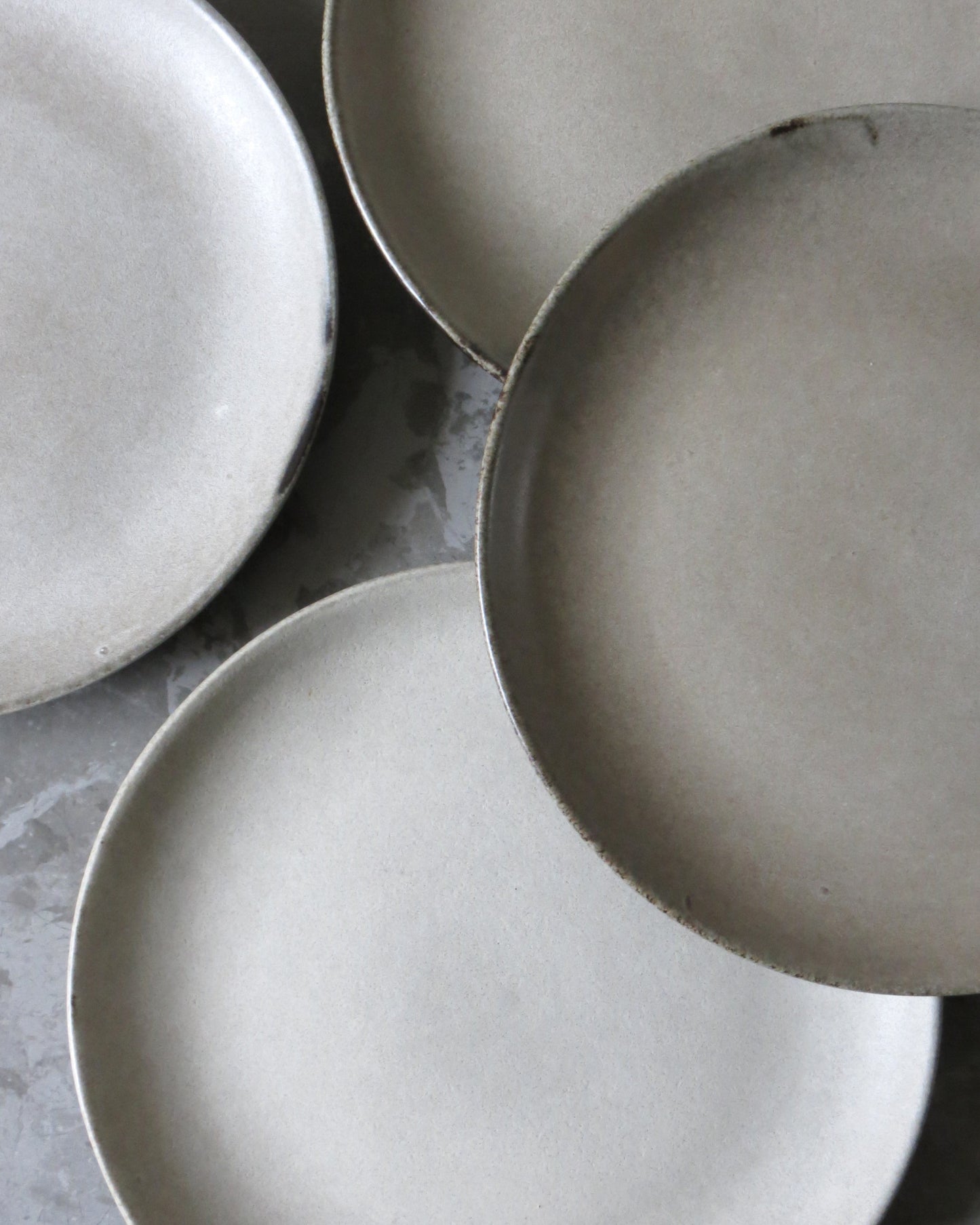 Three ceramic side plates on a grey surface