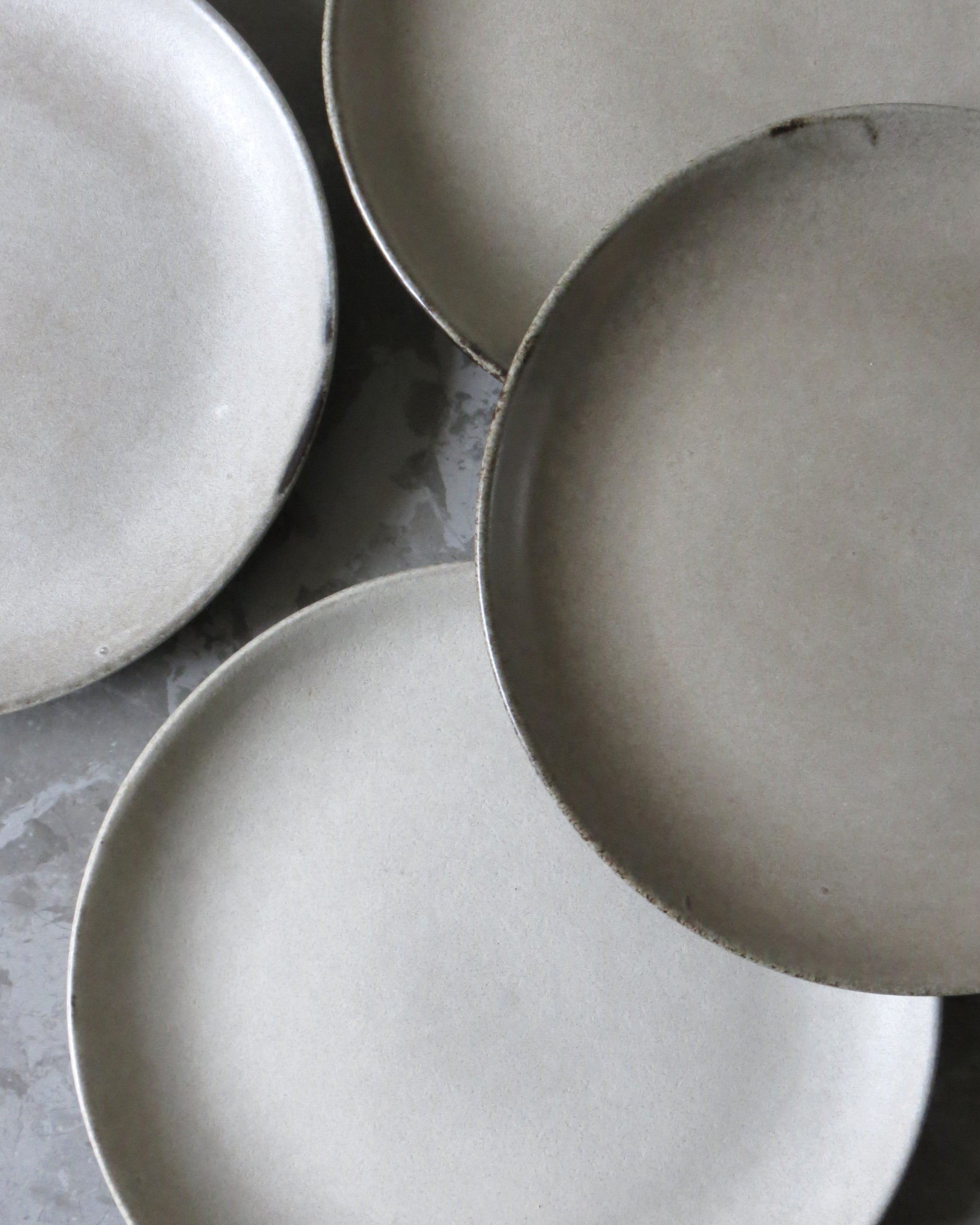 Three ceramic side plates on a grey surface