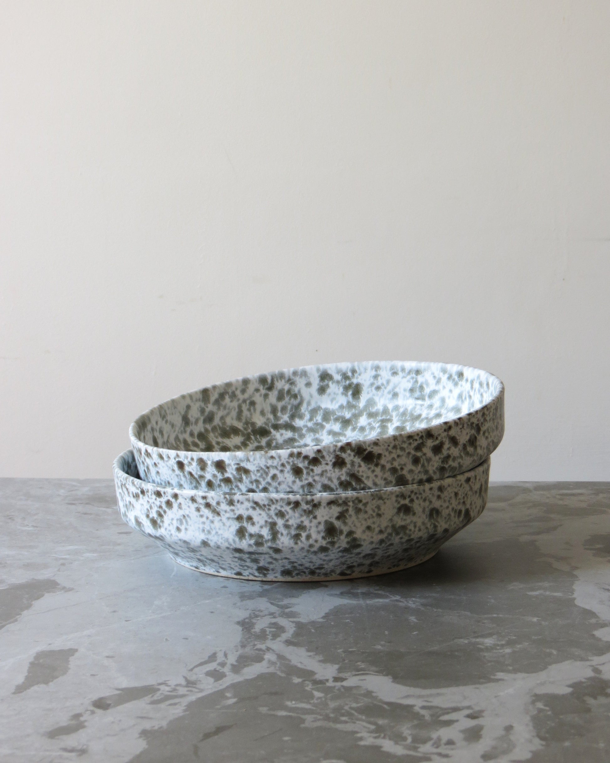 Stack of ceramic bowls with speckled pattern on a grey surface