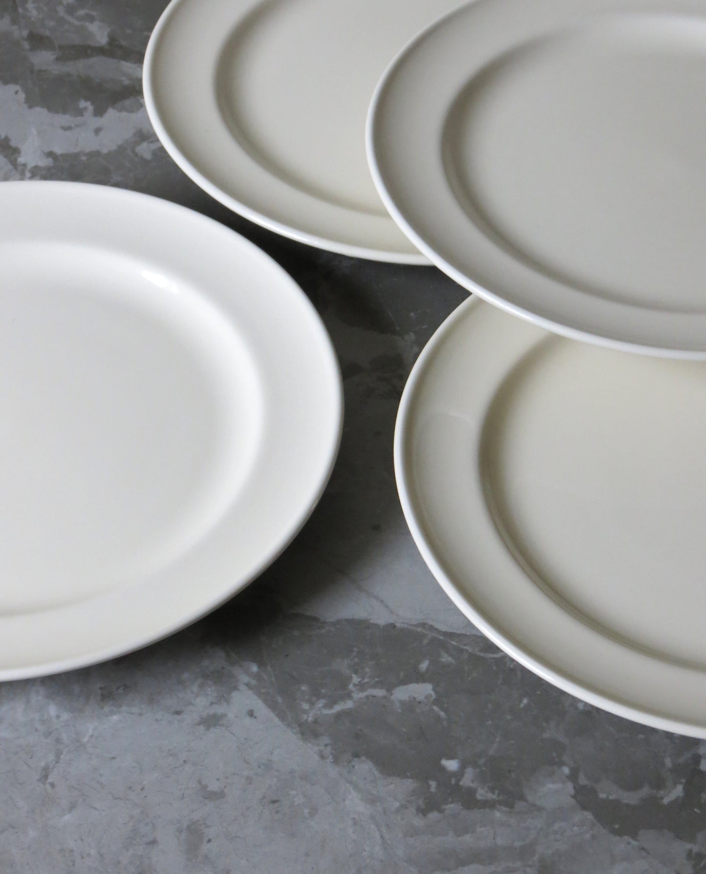Four white plates on a grey concrete surface