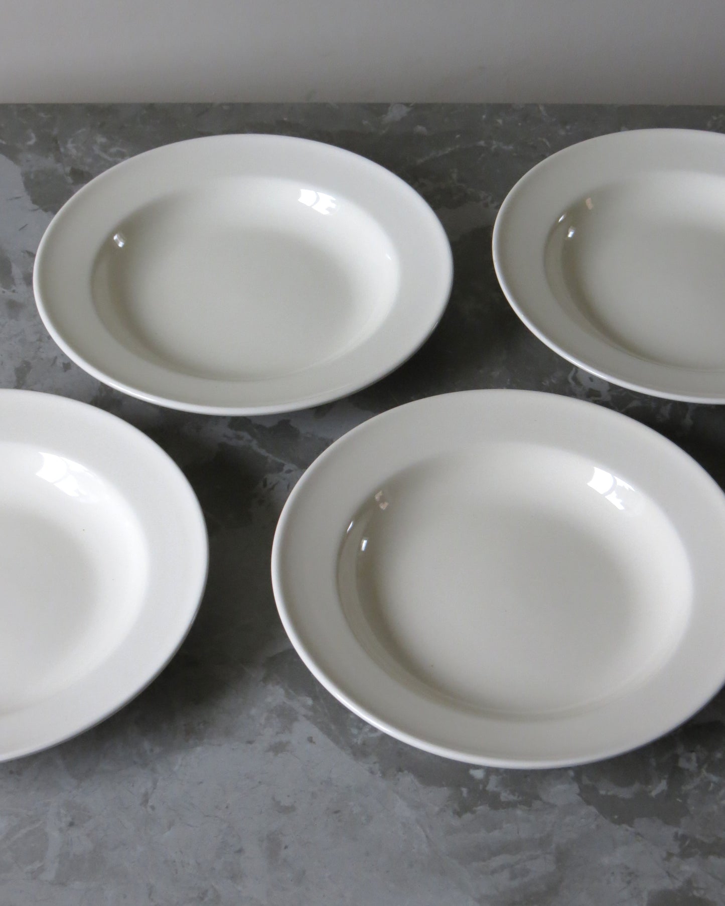 Four white pasta bowls on a grey surface