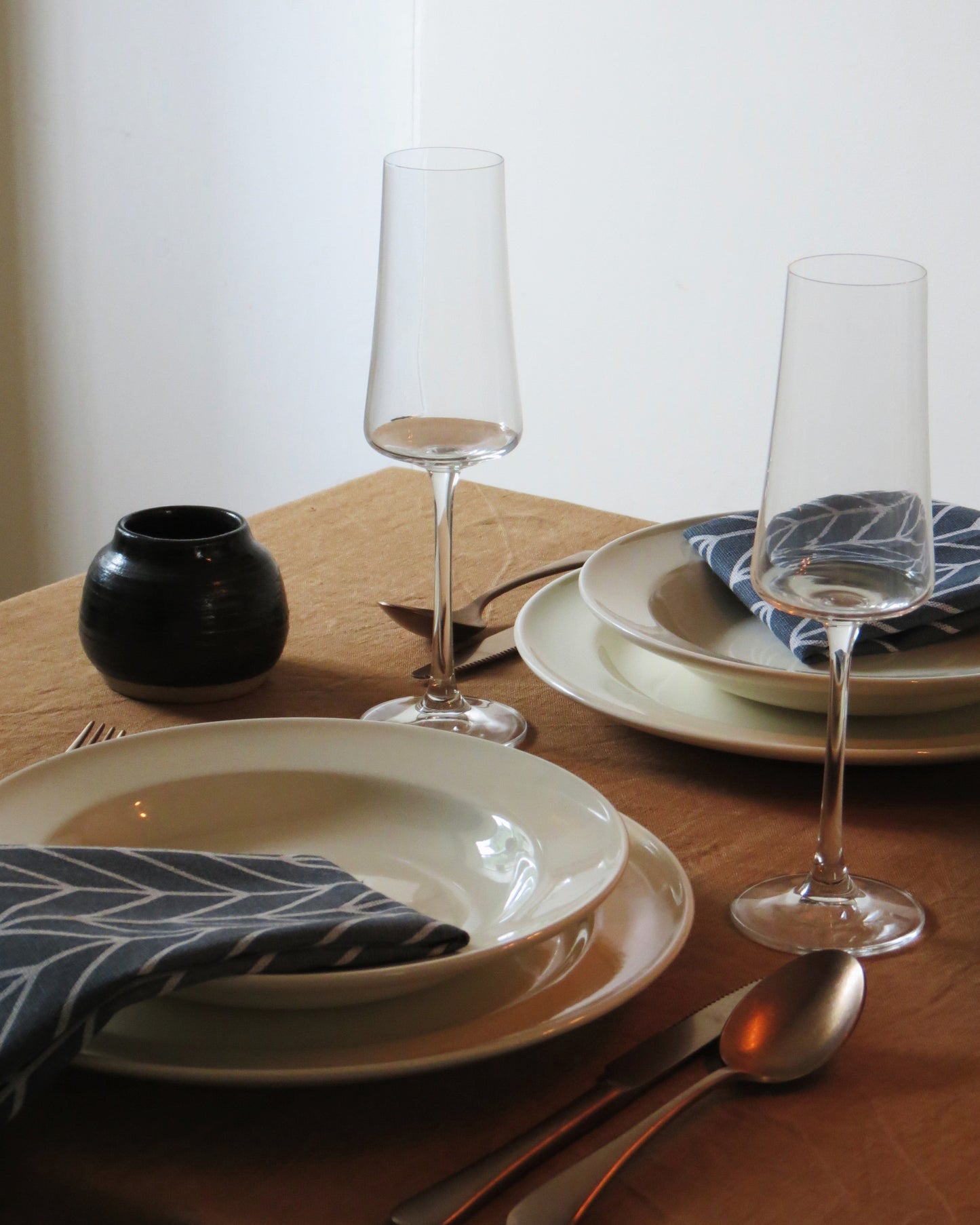 Dinner table setting with plates, glasses, and cutlery on a wooden surface.
