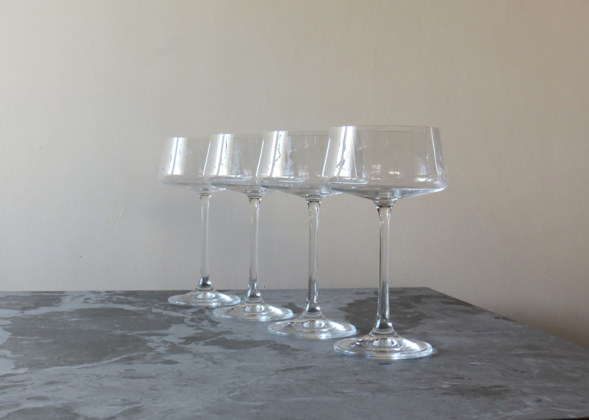 Four clear glass dessert stands on a grey surface with a neutral background