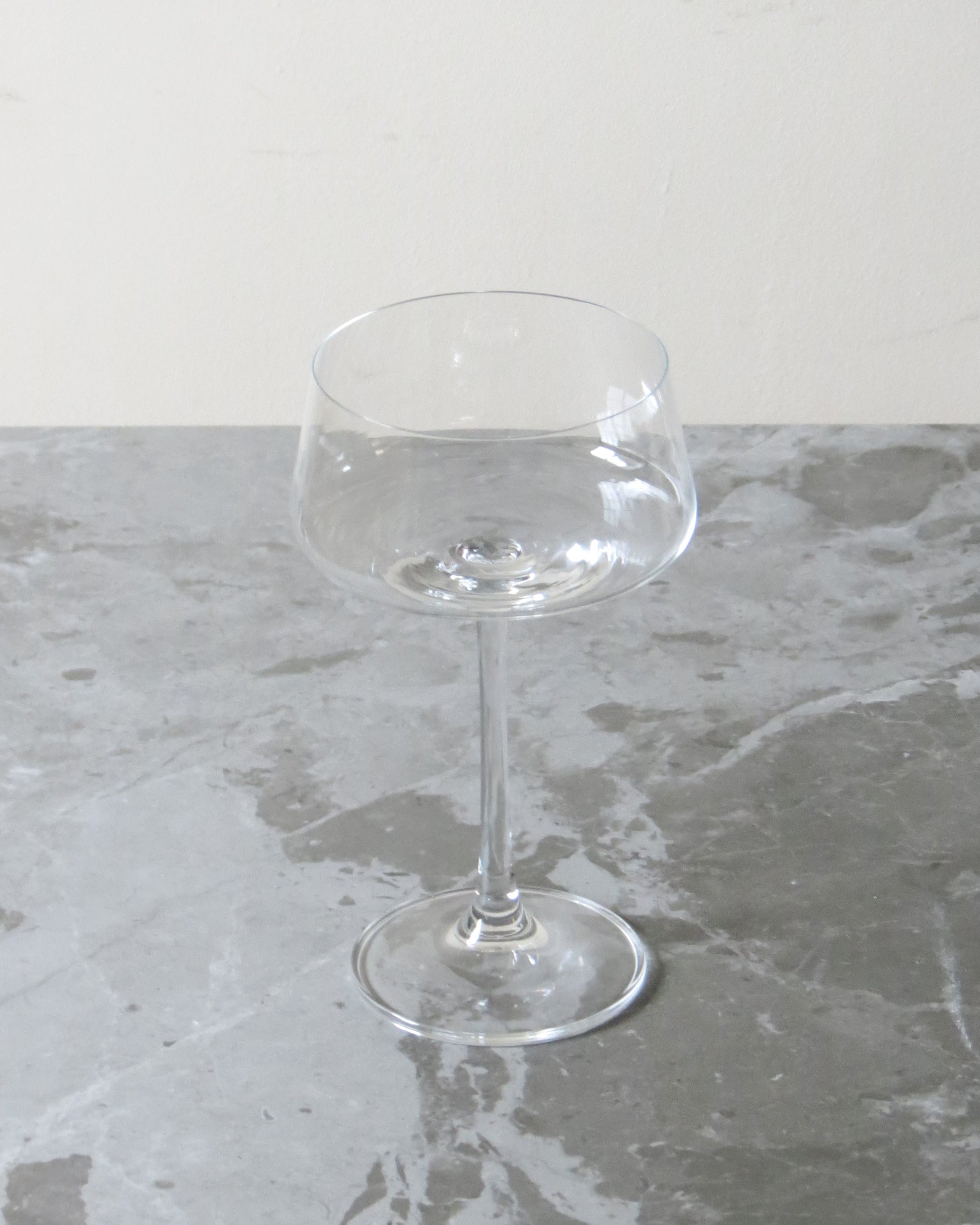 Clear glass coupe on a grey marble surface.