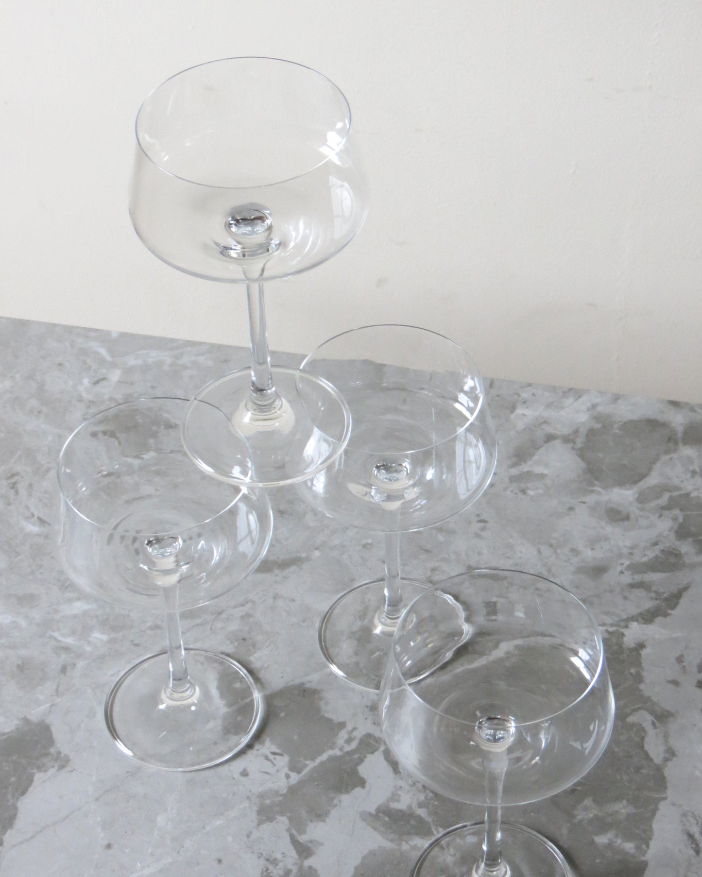 Set of clear glass wine glasses on a stone surface with a white background
