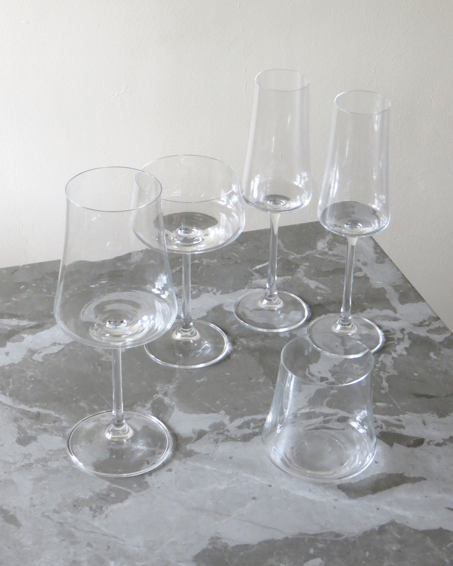 Set of clear wine glasses on a gray surface with a white background