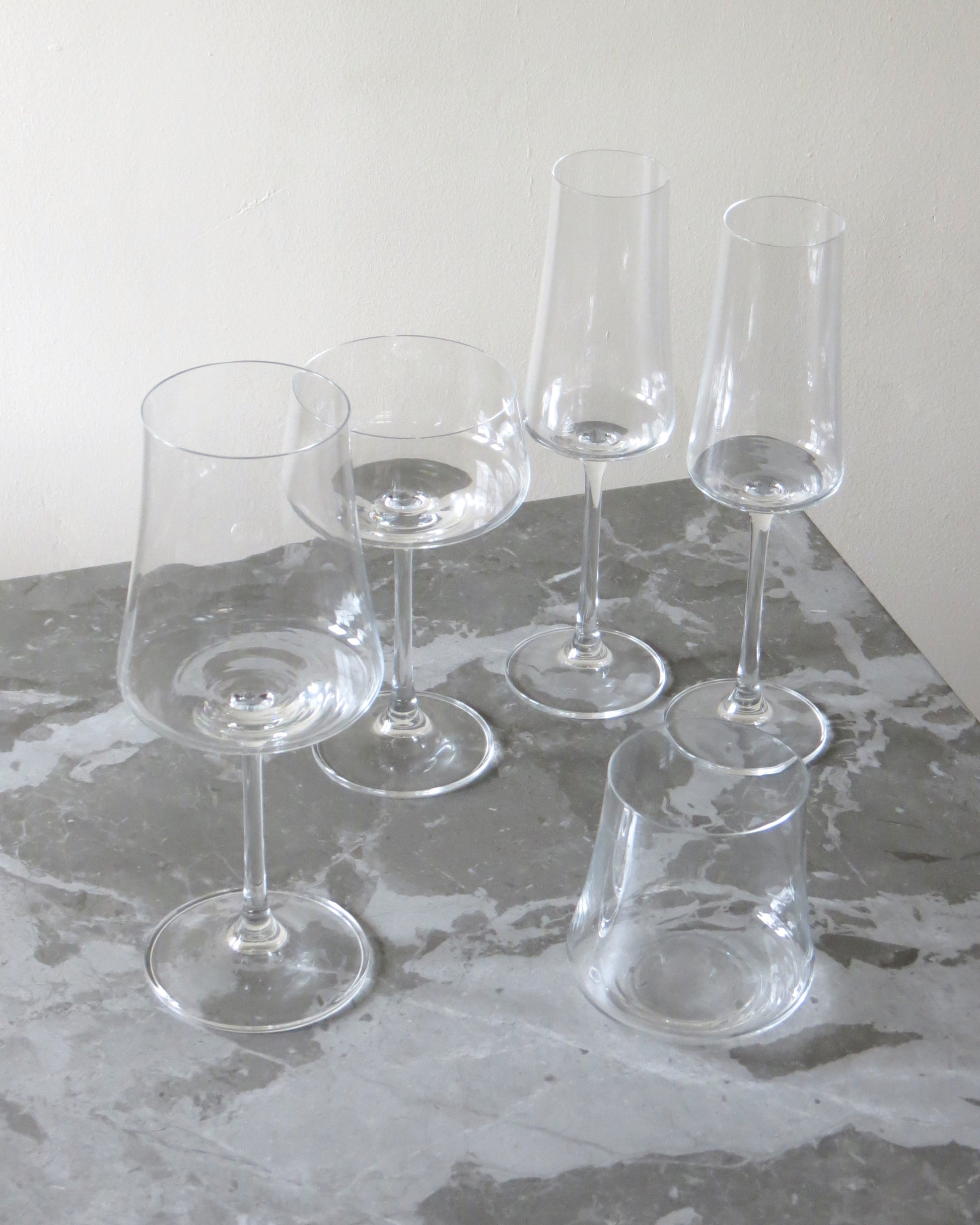 Set of clear wine glasses on a gray surface with a white background