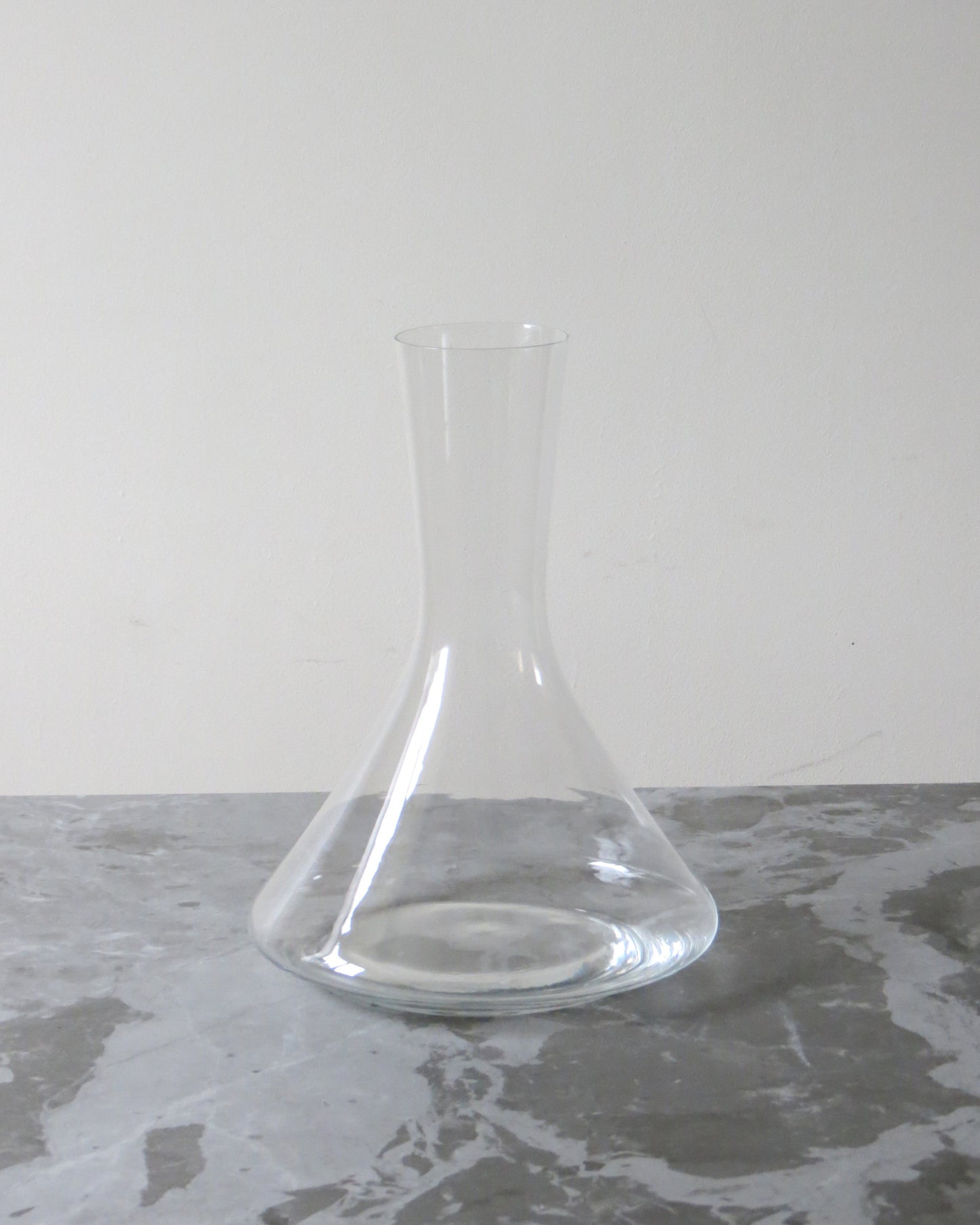 Clear glass decanter on a grey surface with a white background