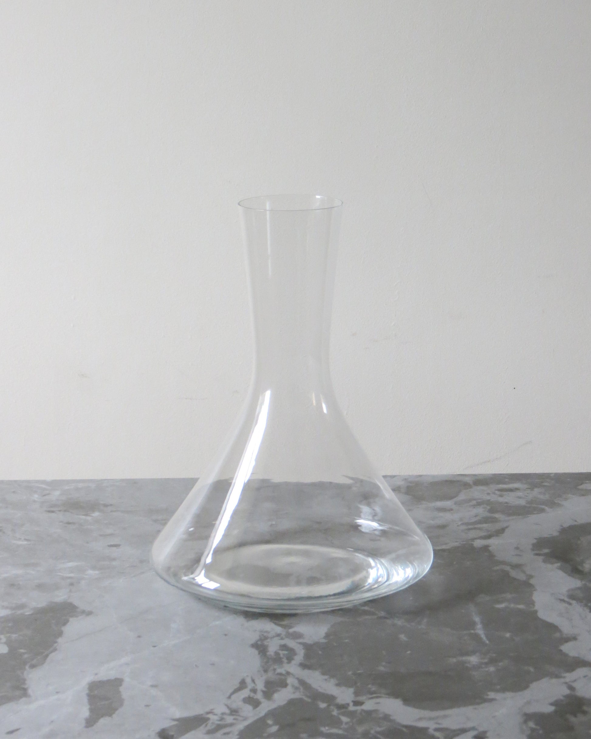 Clear glass decanter on a grey surface with a white background