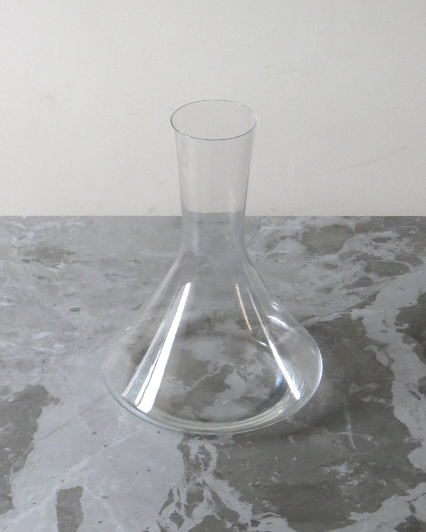 Clear glass decanter on a grey surface with a white background