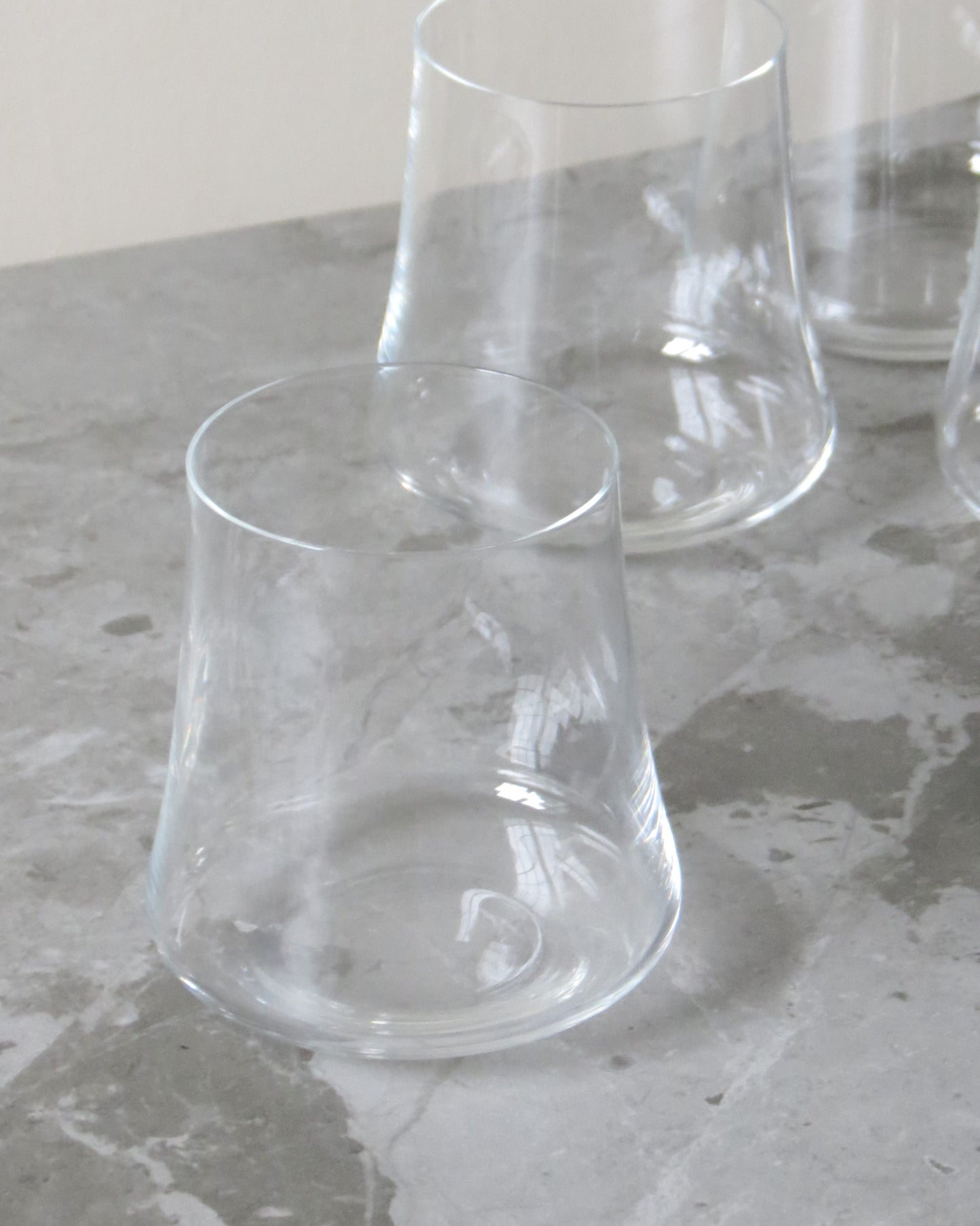 Clear glass tumblers on a textured stone surface.