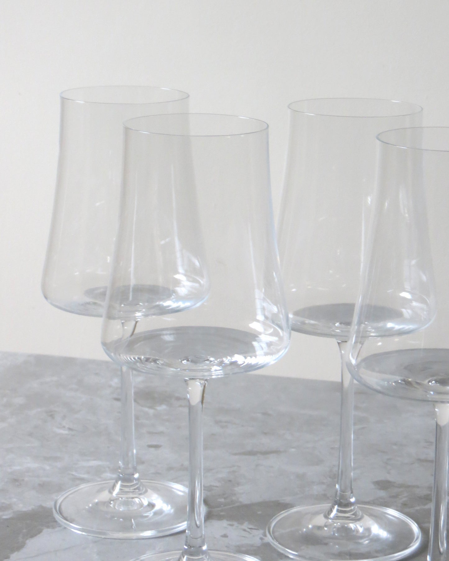 Set of clear wine glasses on a marble surface with a light grey background