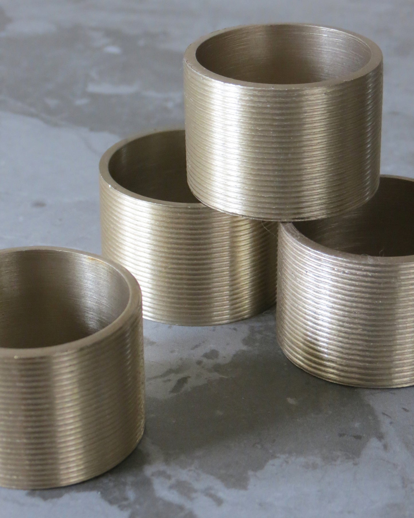 Four metallic cylindrical objects with ribbed texture on a concrete surface