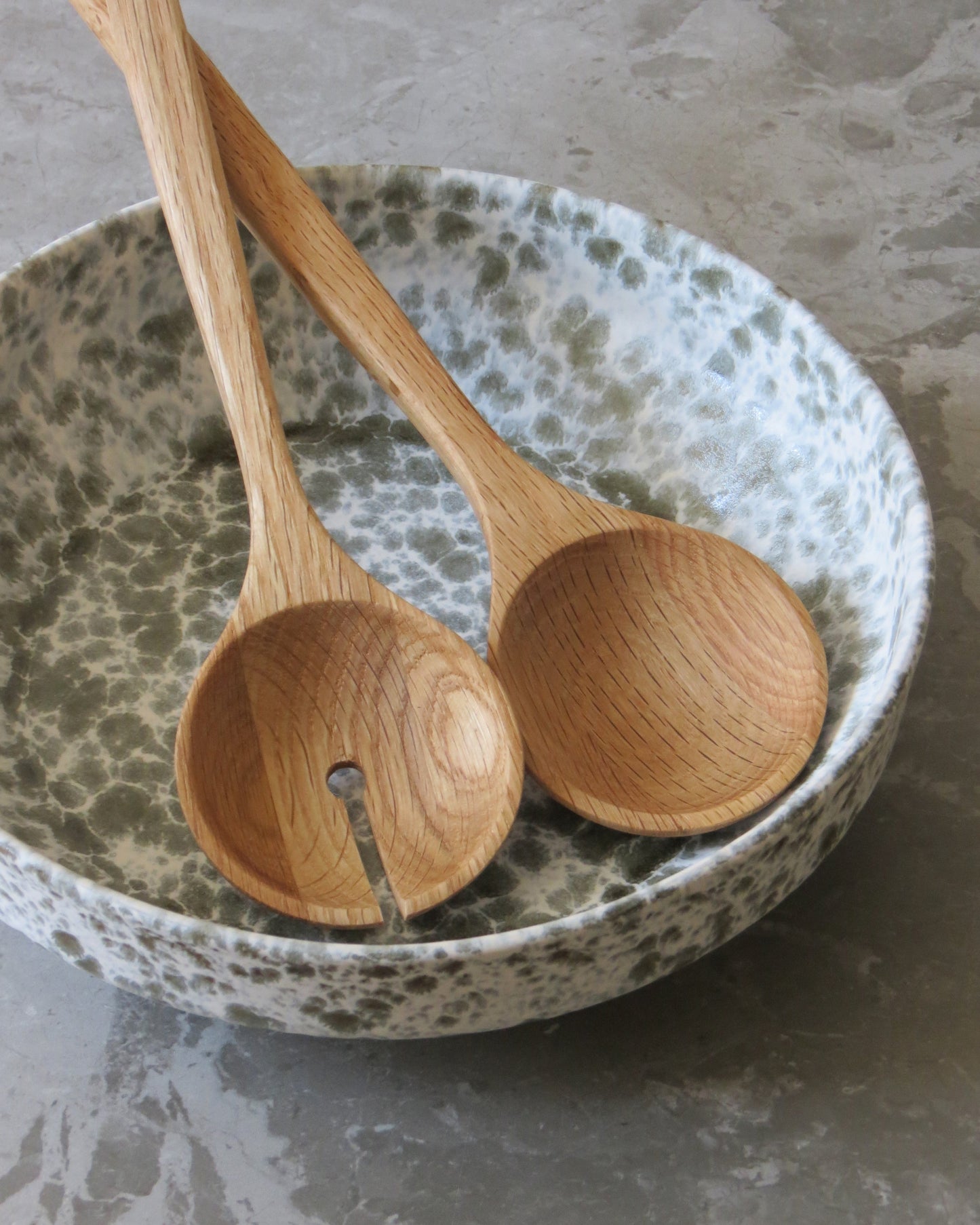 Two wooden spoons on a speckled ceramic plate.