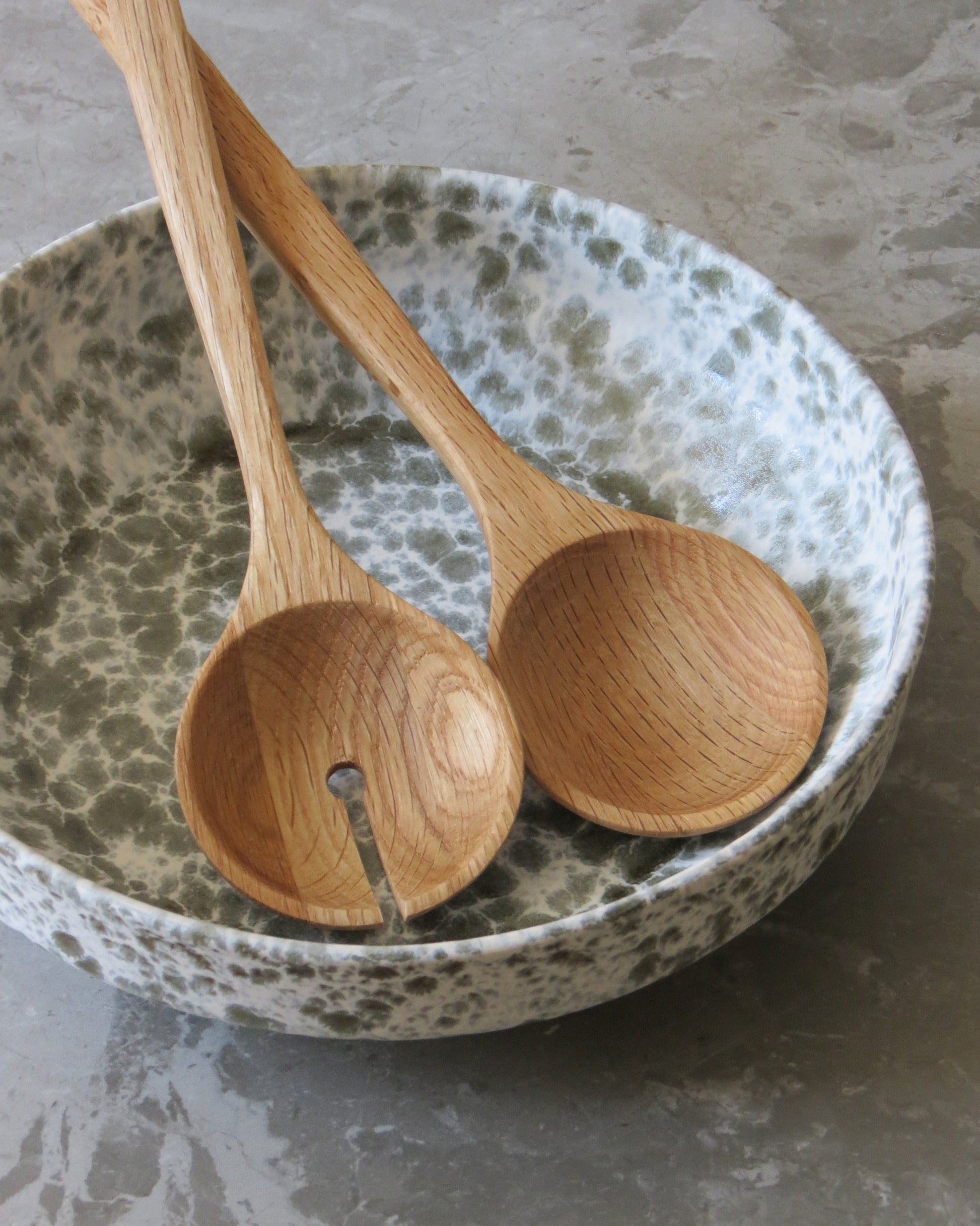 Two wooden spoons on a speckled ceramic plate.