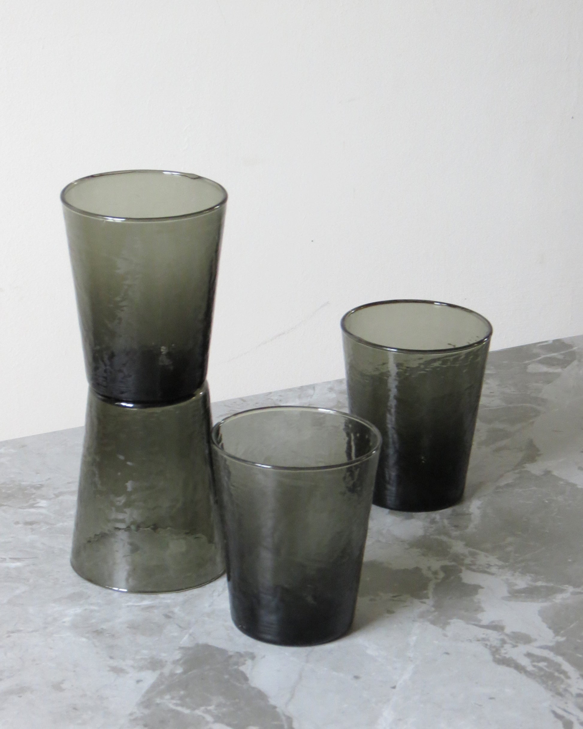 Three smoked glass tumblers on a textured surface.