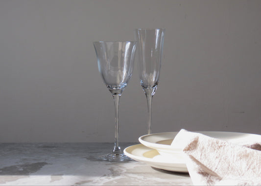 Two clear glass flutes on a marble surface with a neutral background