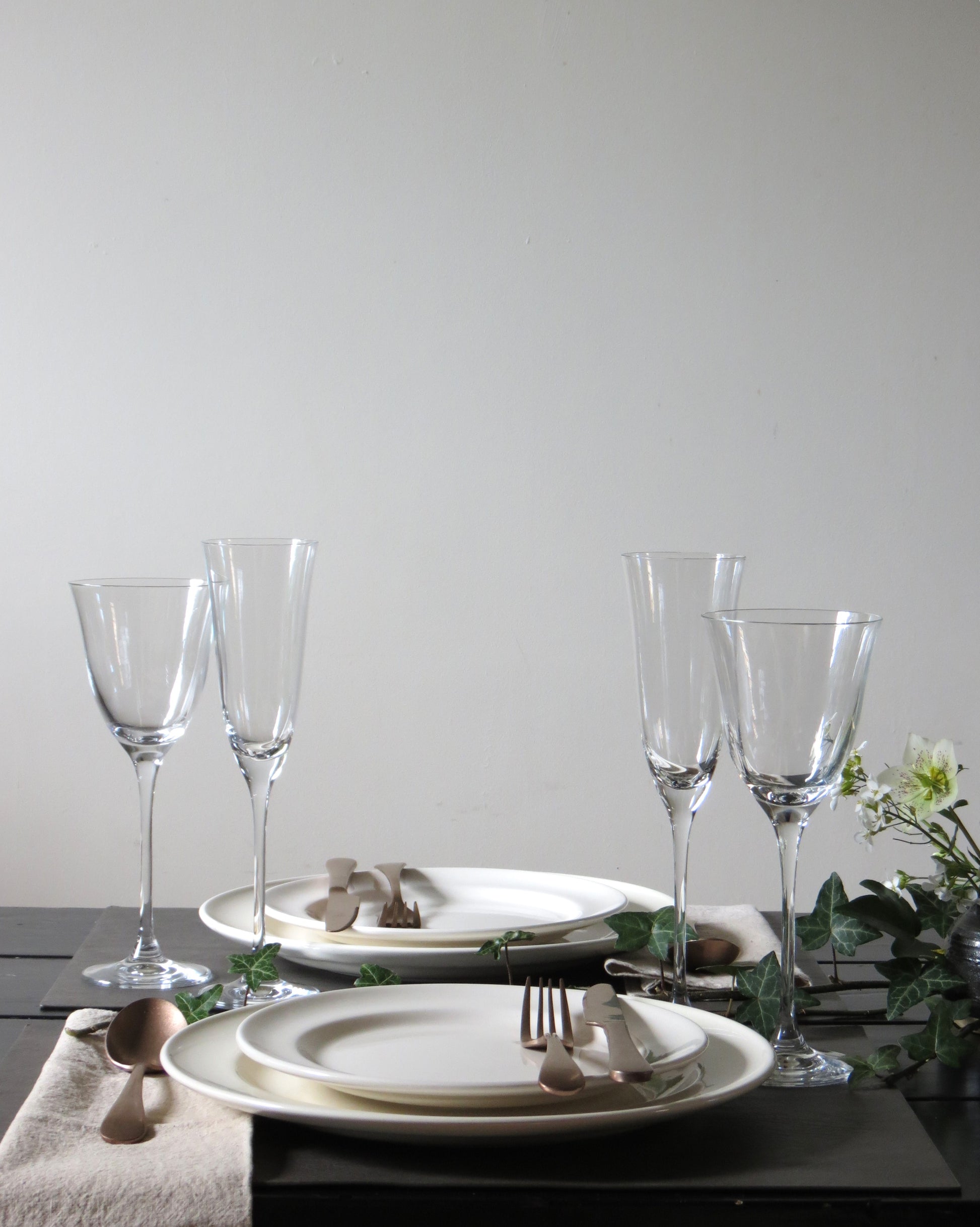 Elegant table setting with plates, cutlery, and glasses on a neutral background.