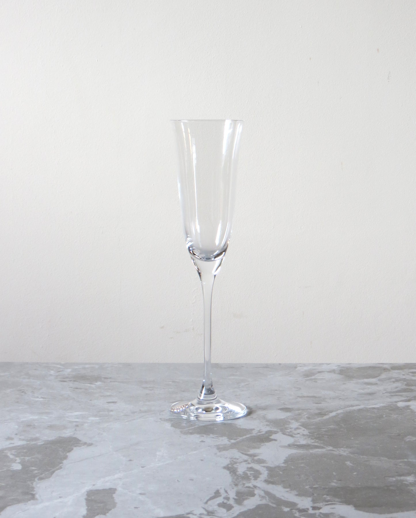 Clear glass flute on a textured surface with a neutral background