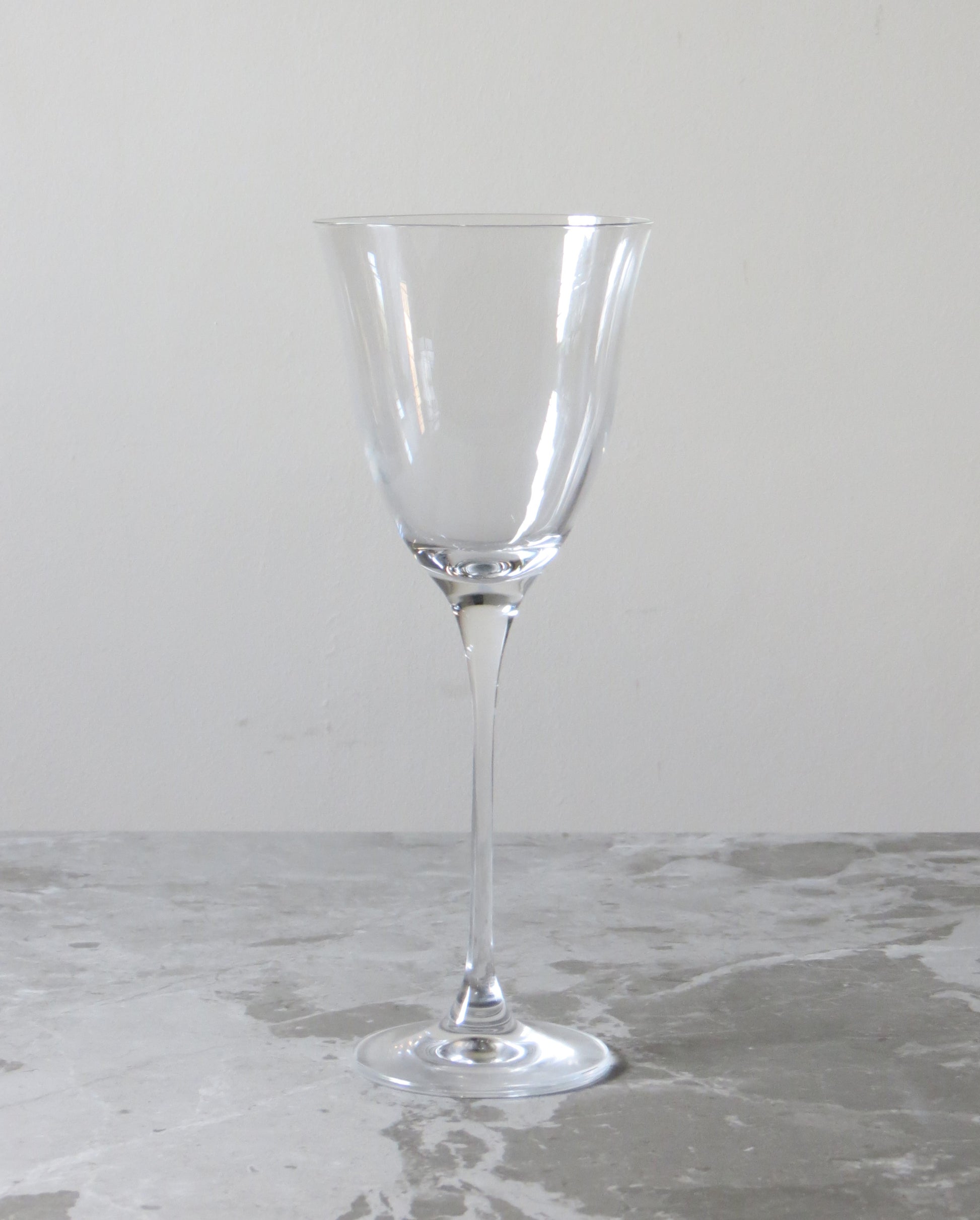 Clear wine glass on a speckled surface with a neutral background.