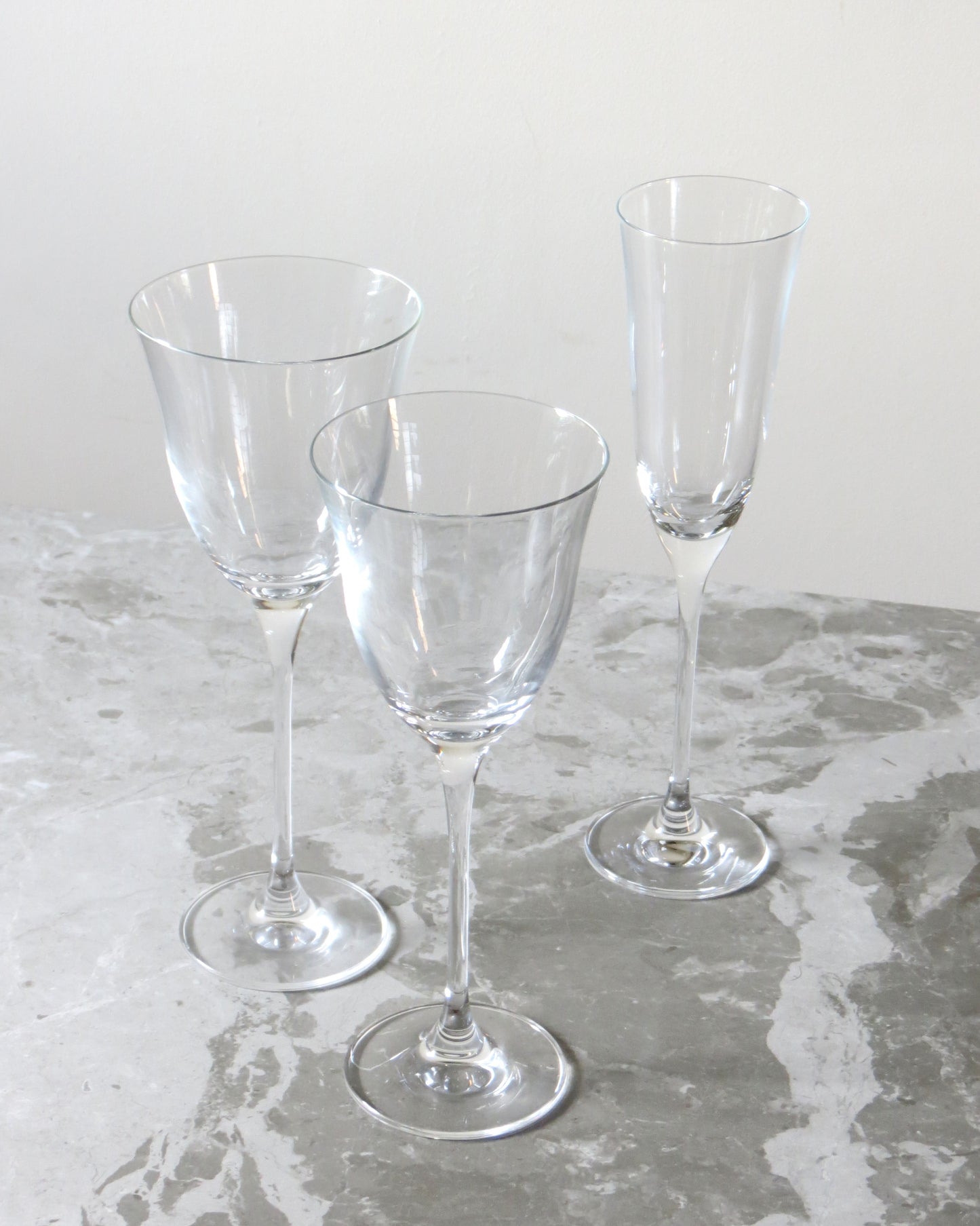 Three clear glass wine glasses on a textured surface.