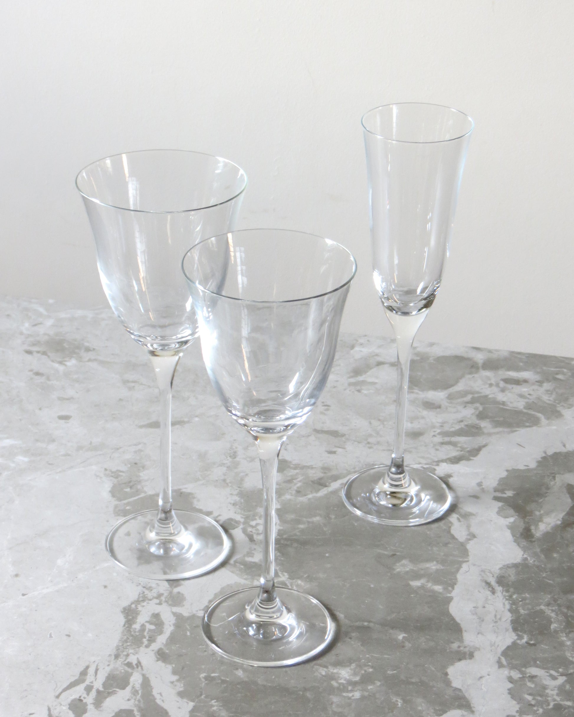 Three clear glass wine glasses on a textured surface.