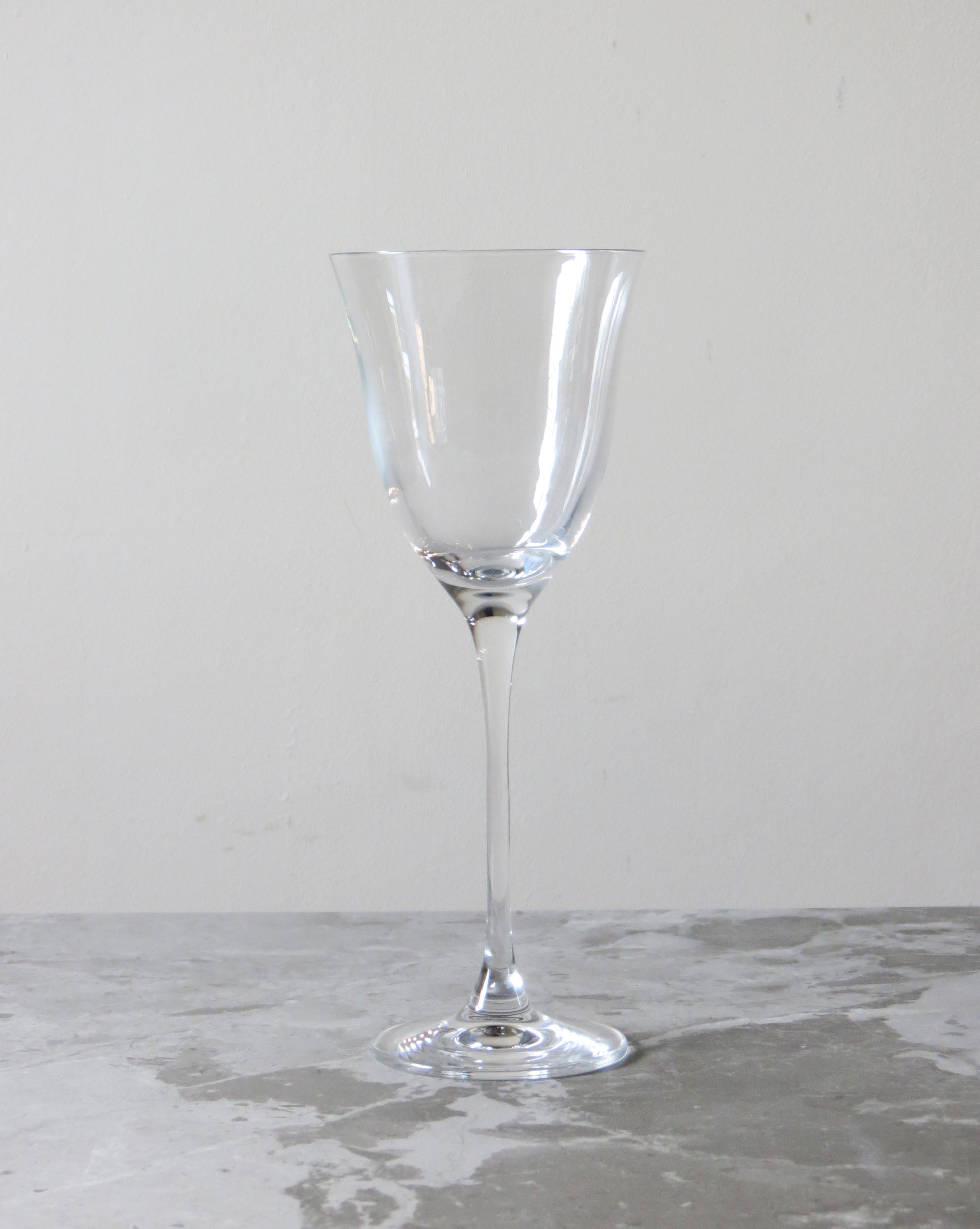 Clear wine glass on a gray surface with a neutral background.