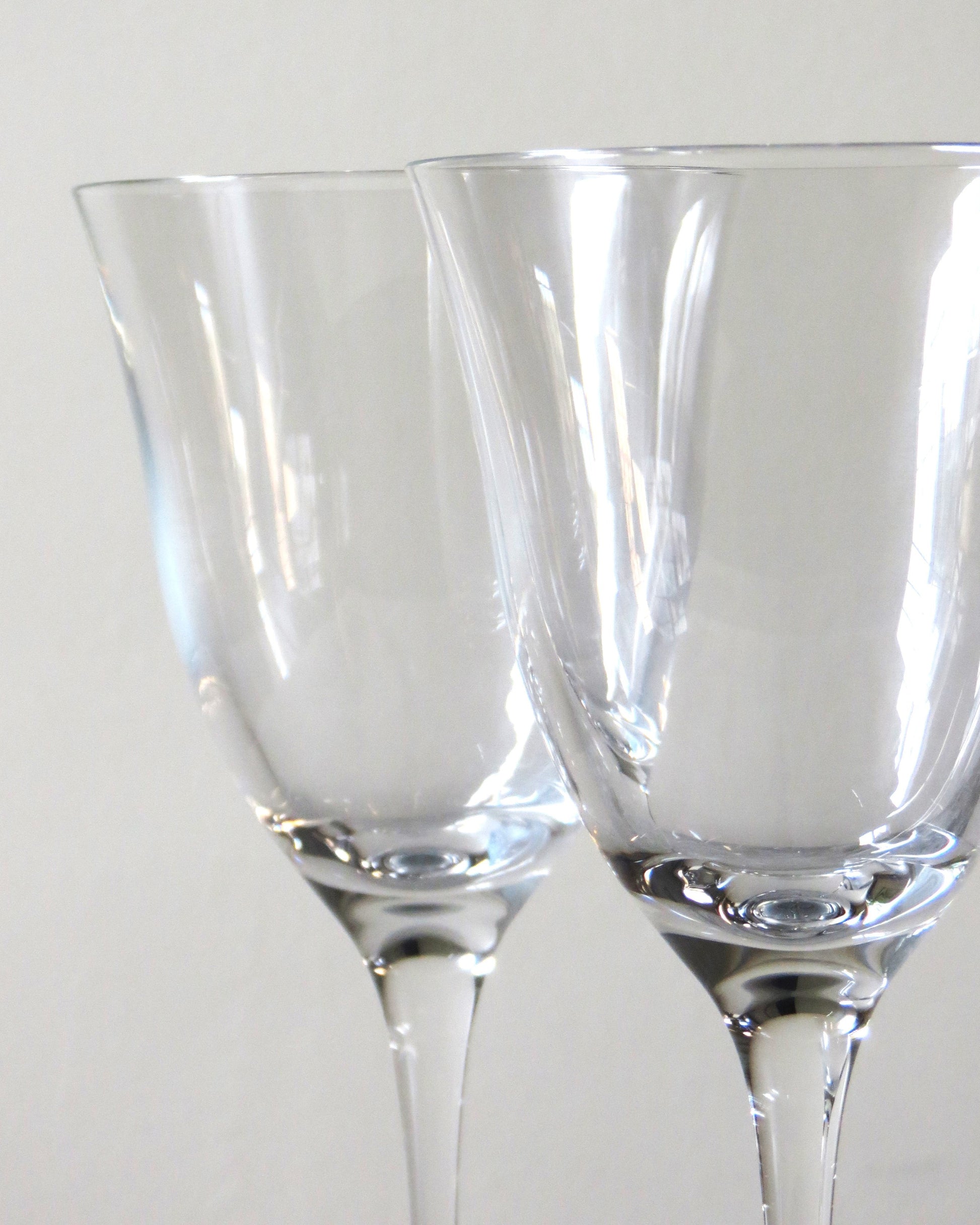 Two clear glass wine glasses on a plain background