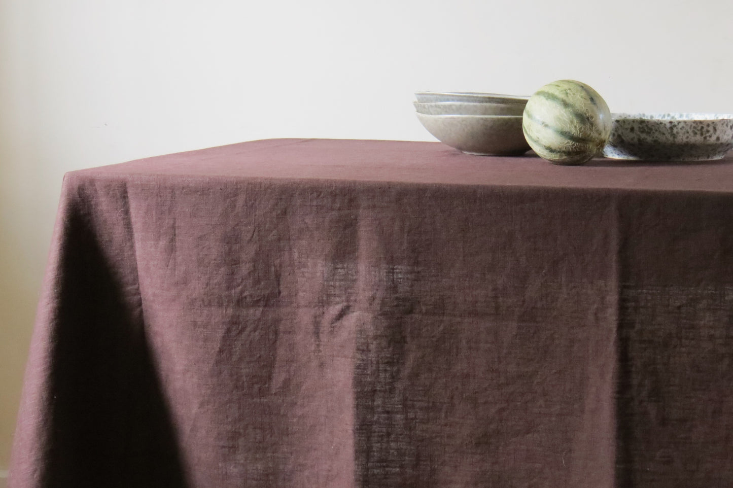 Table covered with a Chocolate Brown Tablecloth, set with bowls and a watermelon.