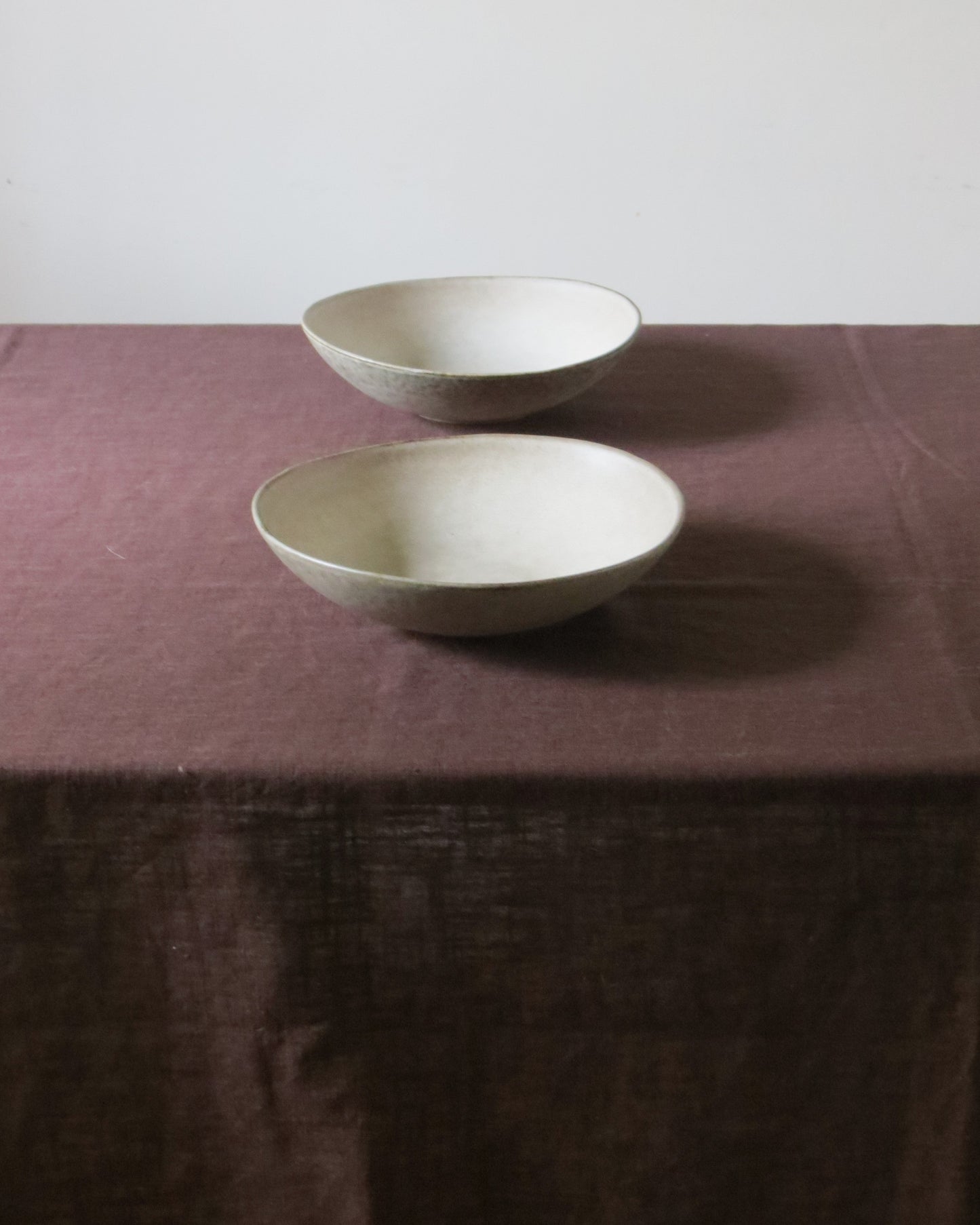 Two ceramic bowls on a textured brown surface with a white background